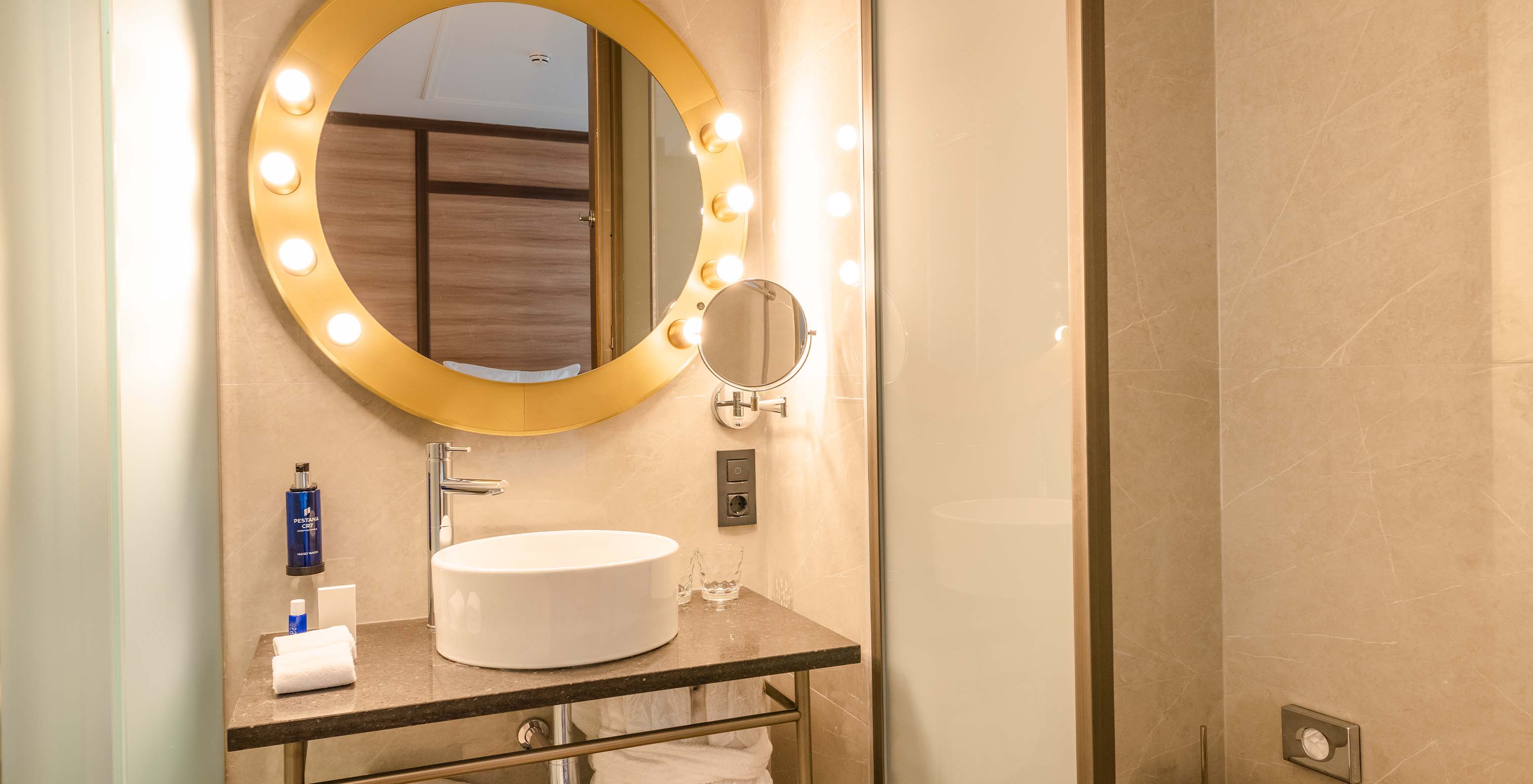 The Superior Room at Pestana CR7 Gran Vía Madrid includes a bathroom with a round mirror and sliding shower doors