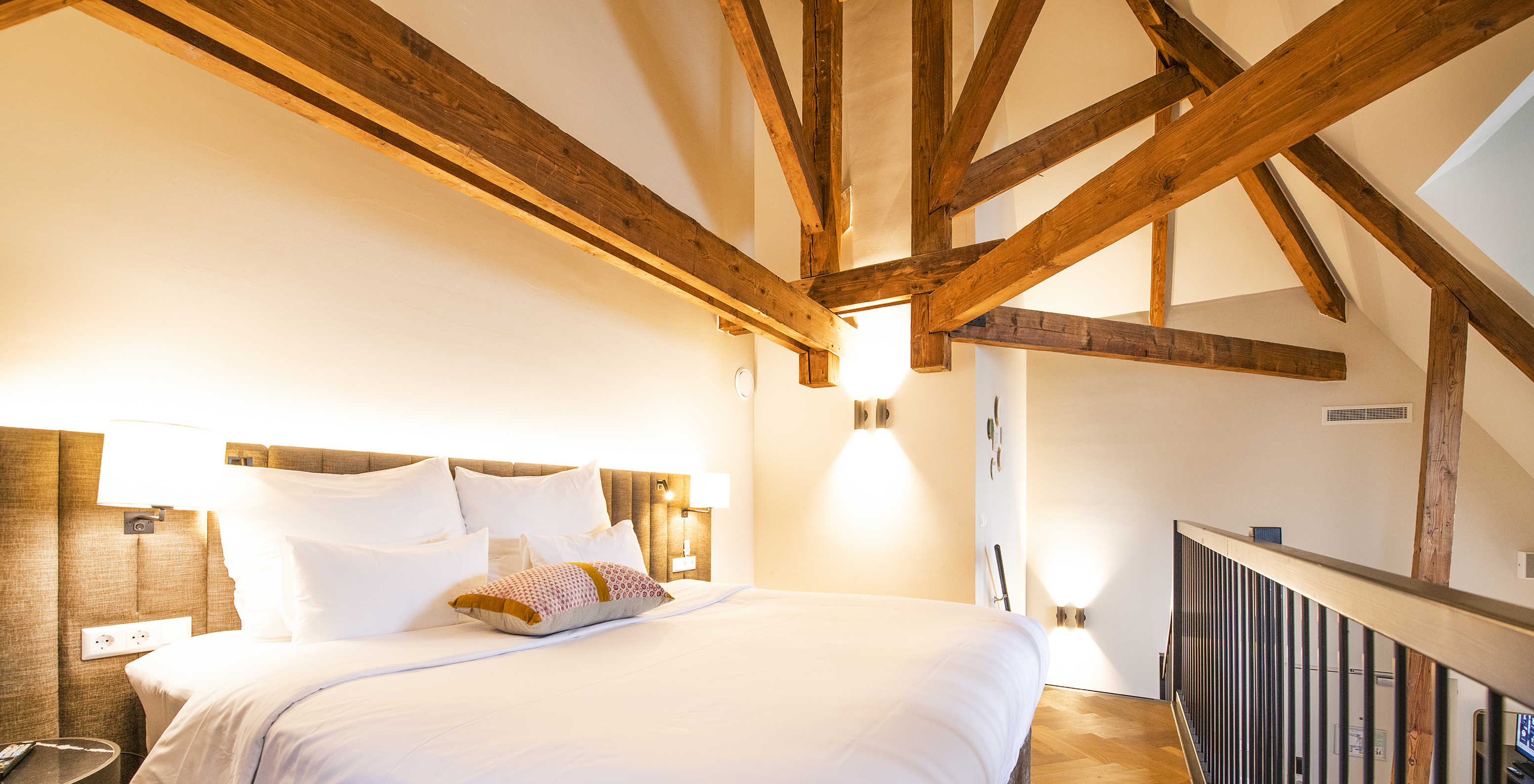 Clock Tower Suite at Pestana Amsterdam Riverside has a double bed, with lamp, and wooden beams on the walls