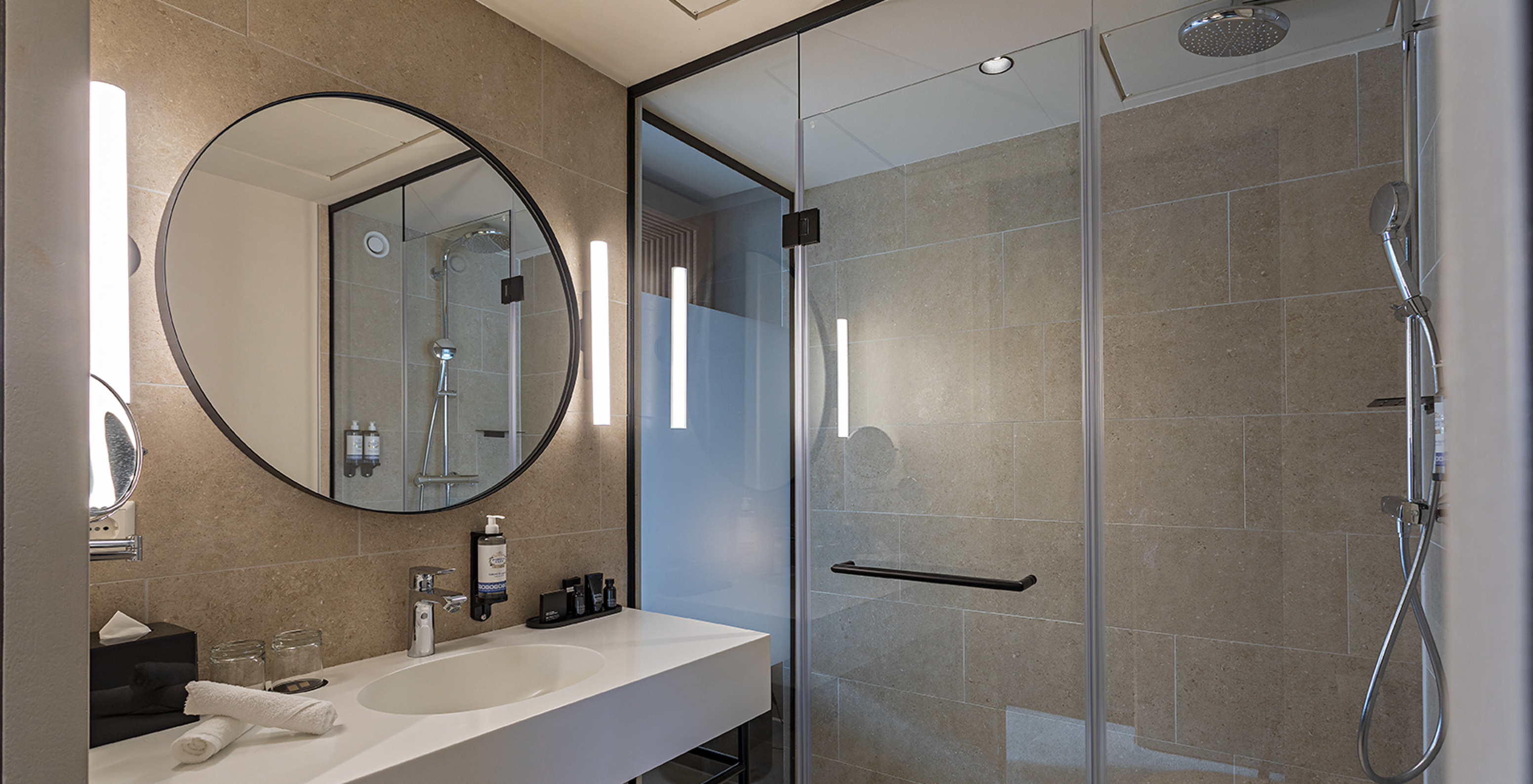 Executive room at Pestana Amsterdam Riverside has a bathroom with mirror, sink, towels and shower