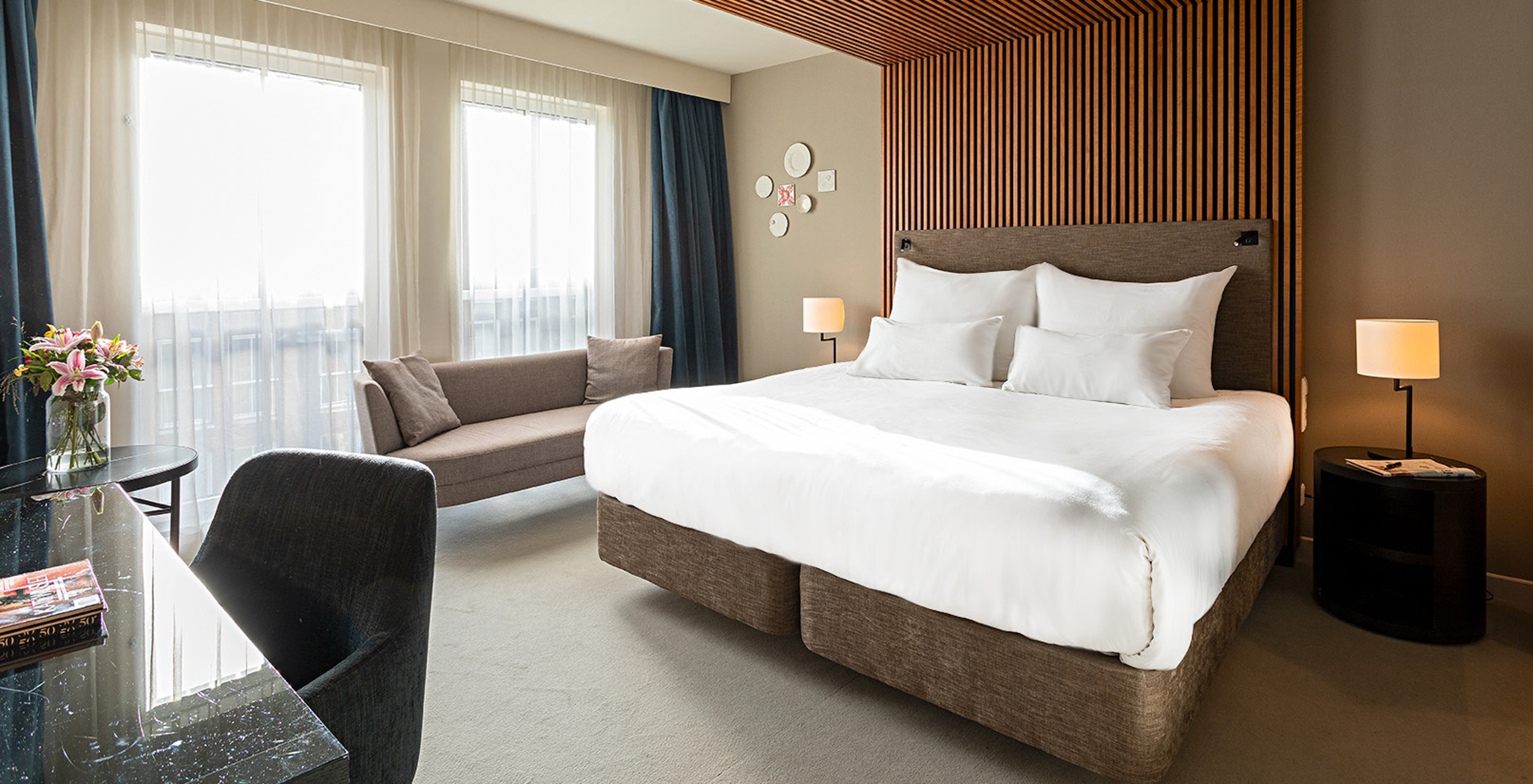 Executive room at Pestana Amsterdam Riverside has a double bed, a sofa, and a bedside table with lamp