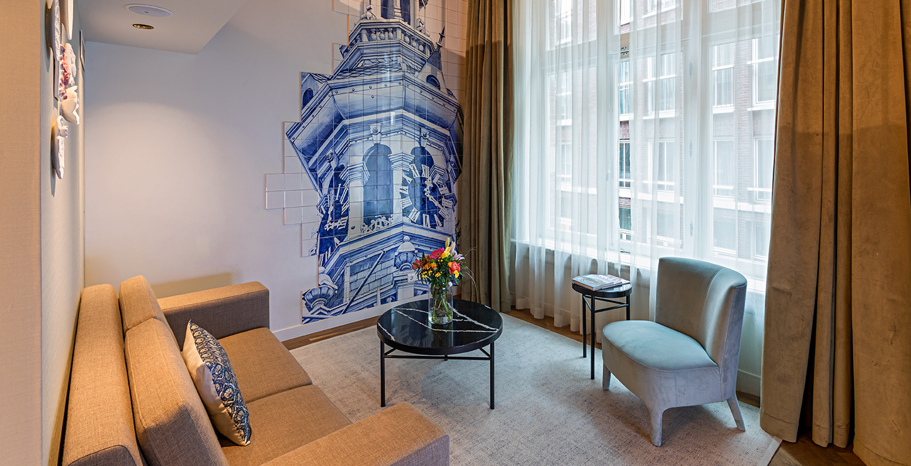 Mezzanine Suite at Pestana Amsterdam Riverside has a living room with sofa, coffee table with flowers, and tiles