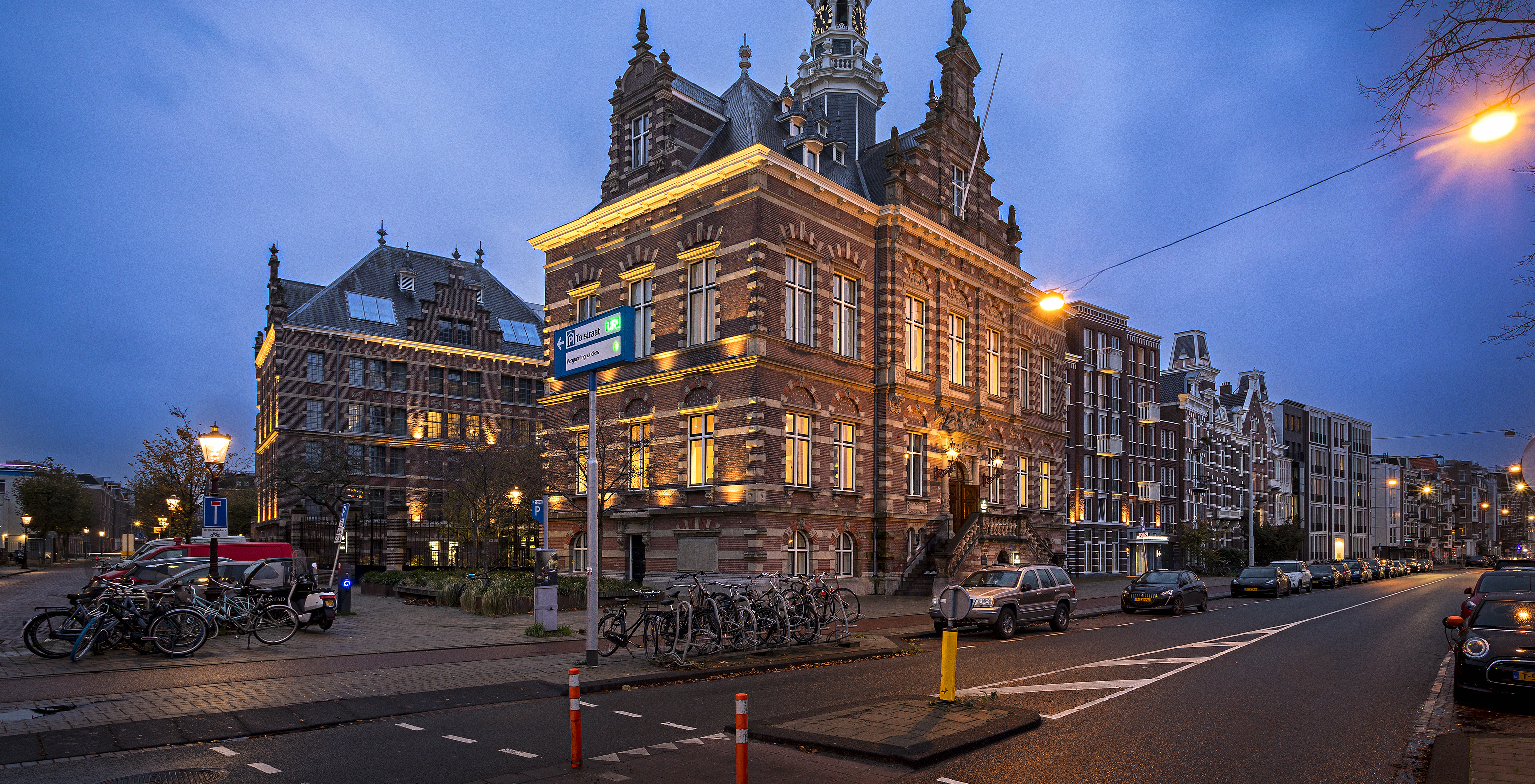 Night exterior of Pestana Amsterdam Riverside, red brick, parked bikes, yellow lights