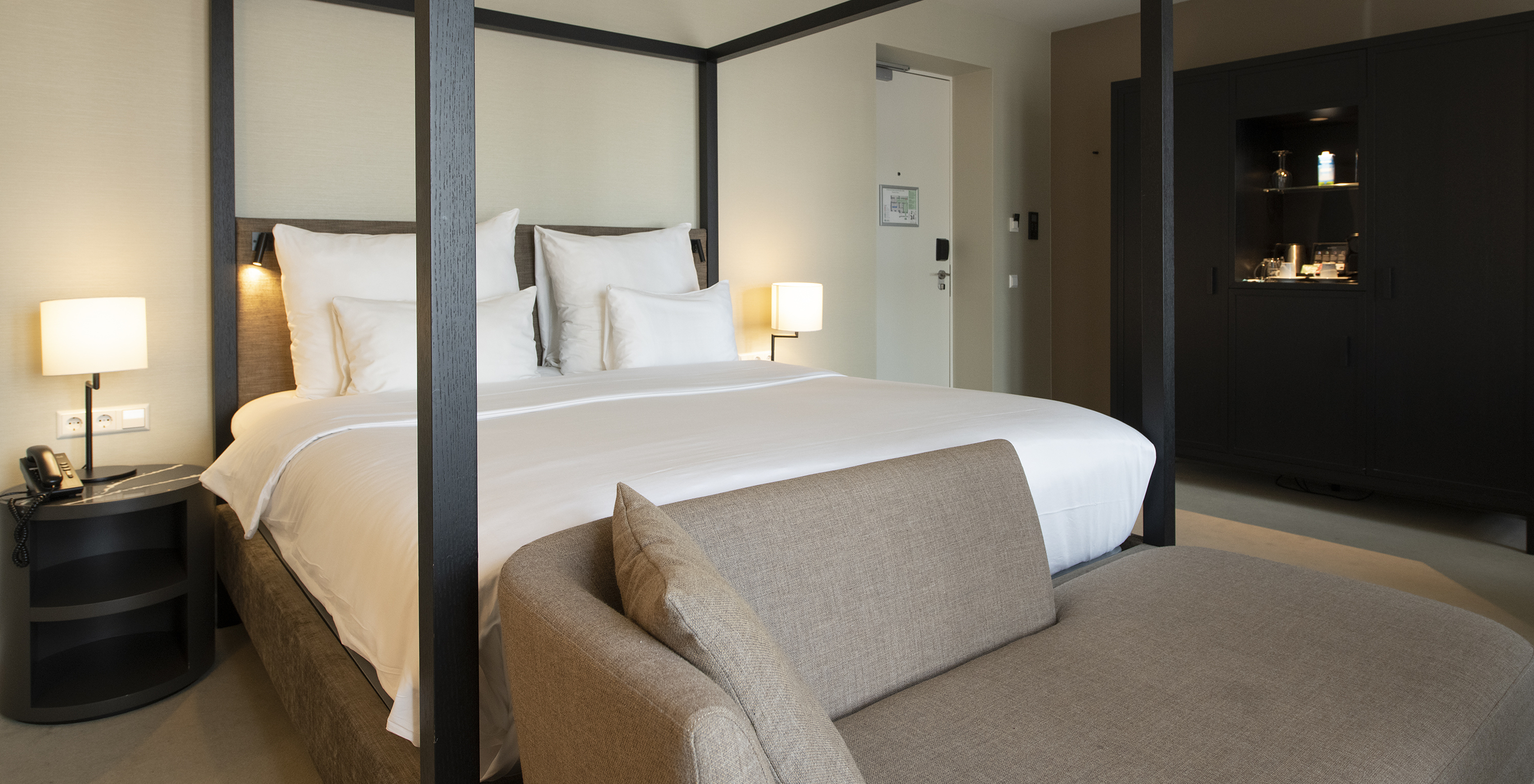 Premium Deluxe room at Pestana Amsterdam Riverside has a double bed with canopy, bedside table, and a sofa