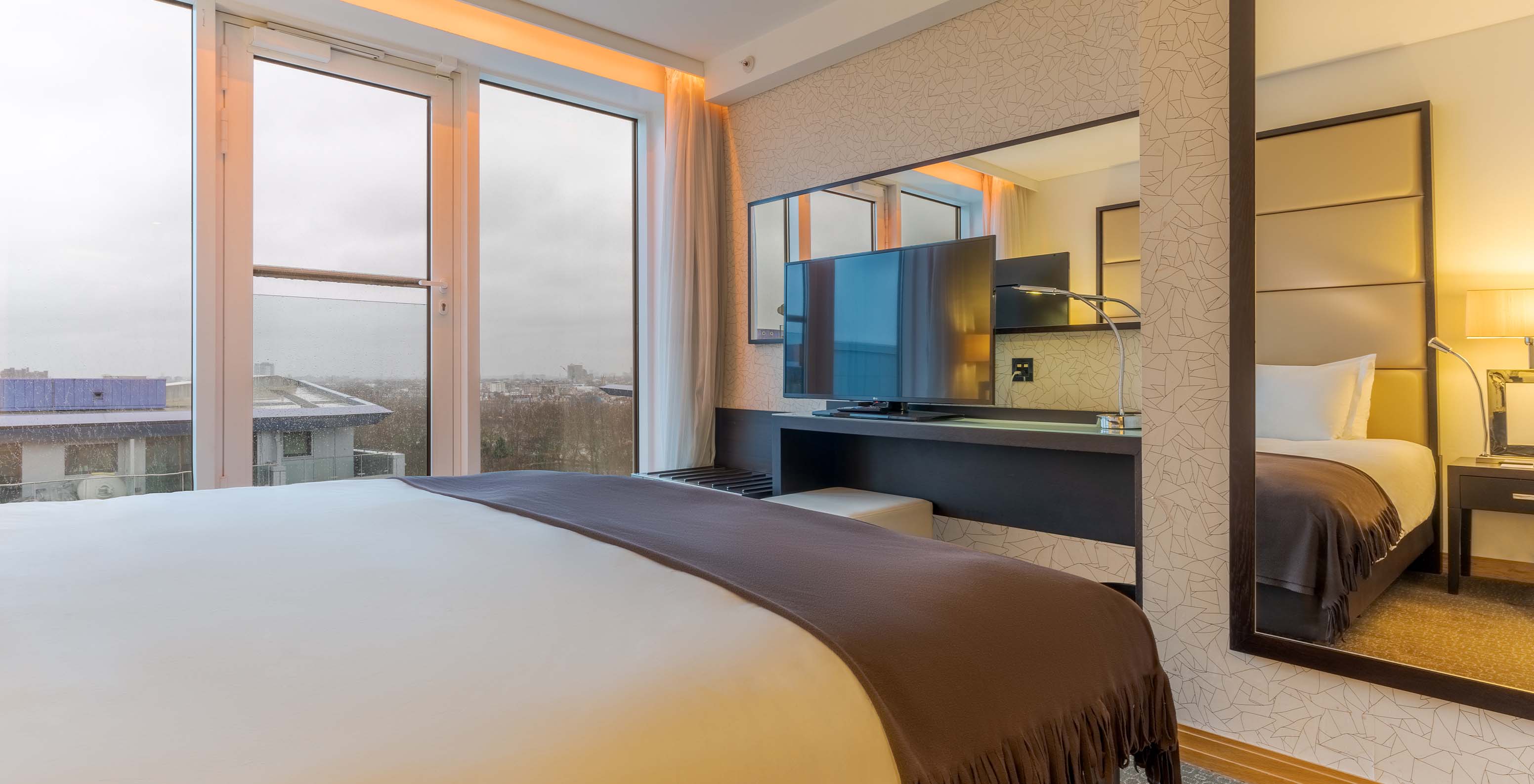 The Executive Suite with 1 Bedroom at Pestana Chelsea Bridge has a double bed, a desk with a TV, and city windows