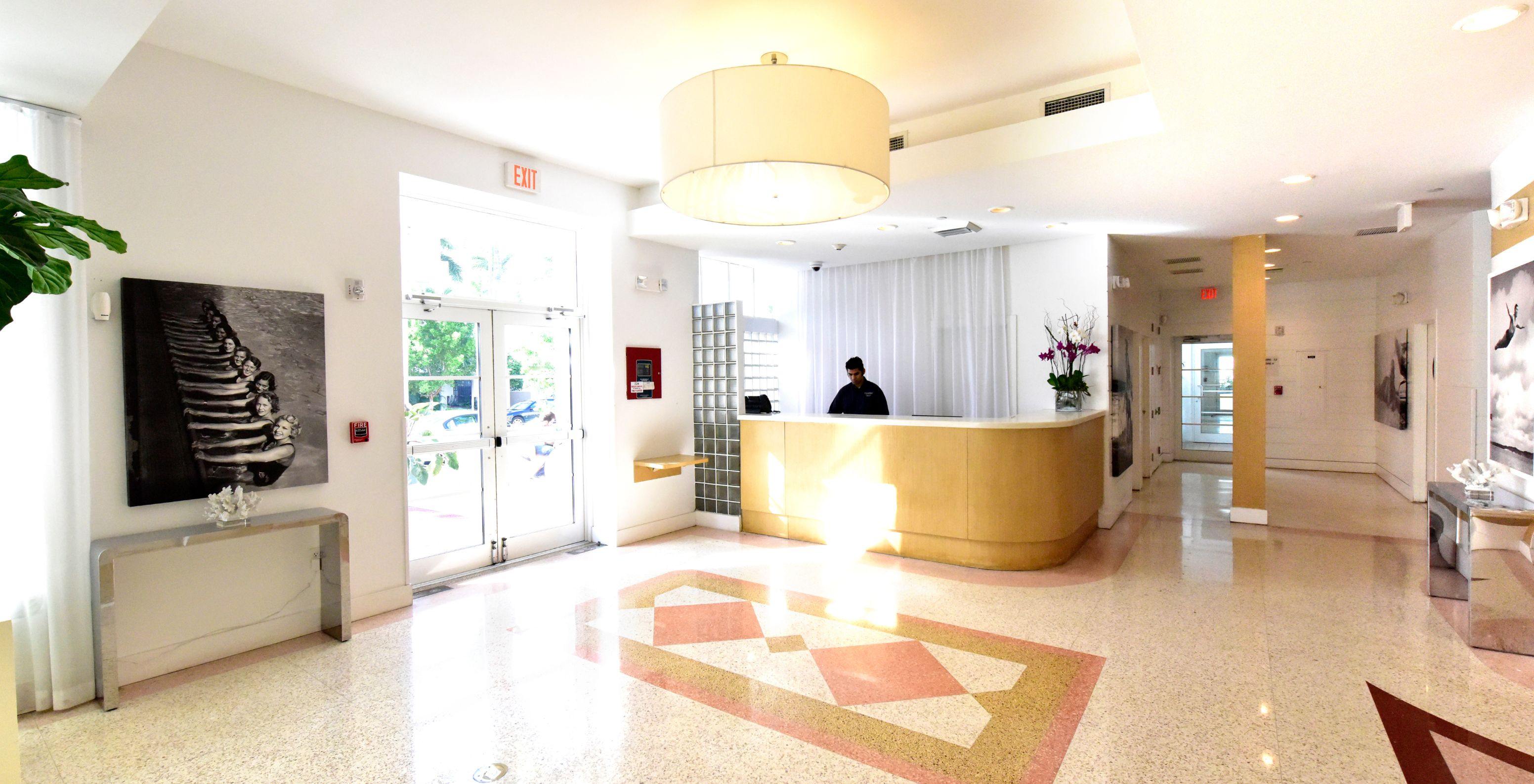 Hotel reception area with mosaic flooring, with a staff member ready to assist guests