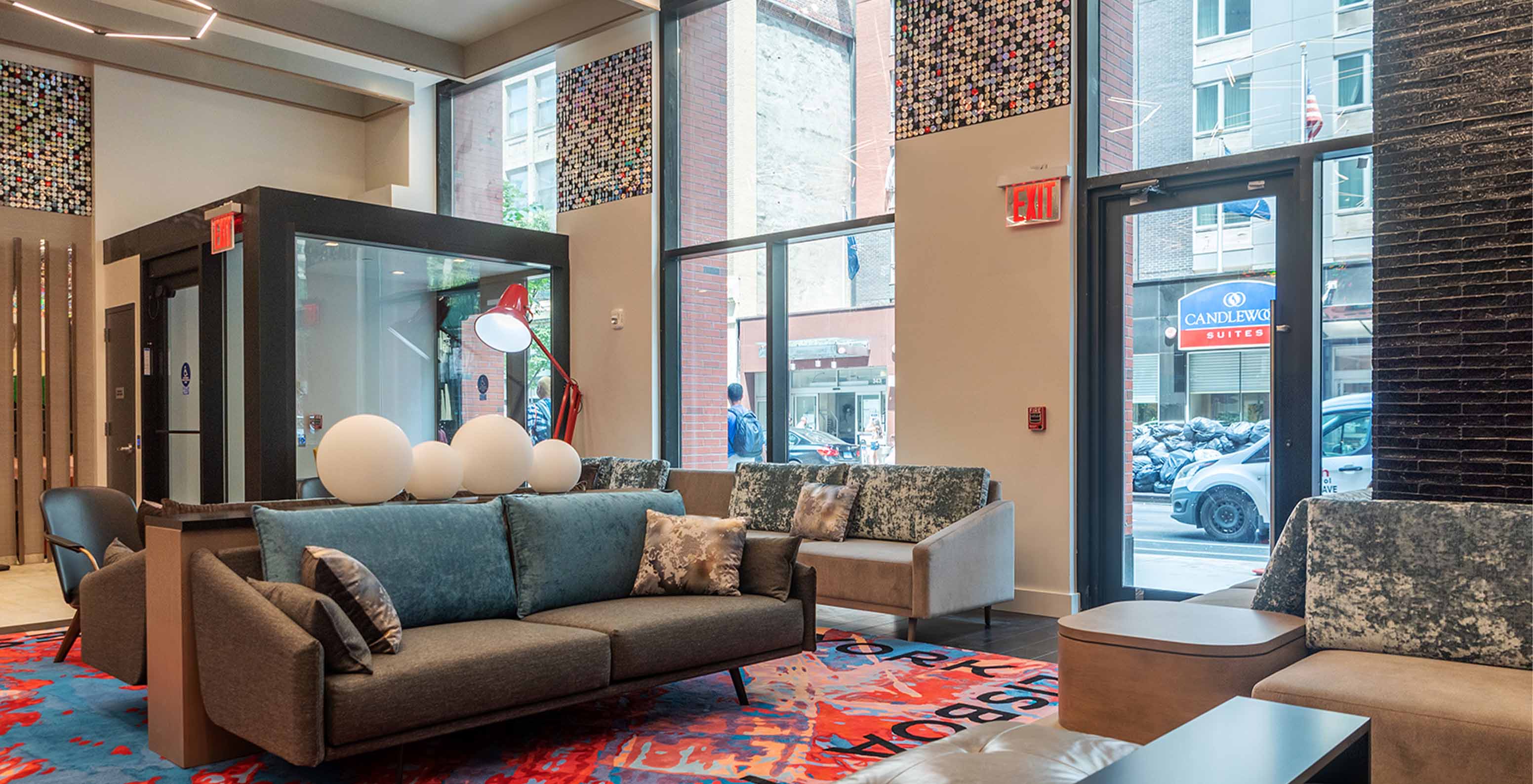 Entrance hall of Pestana CR7 Times Square with sofas, vibrant carpet, and an entrance door