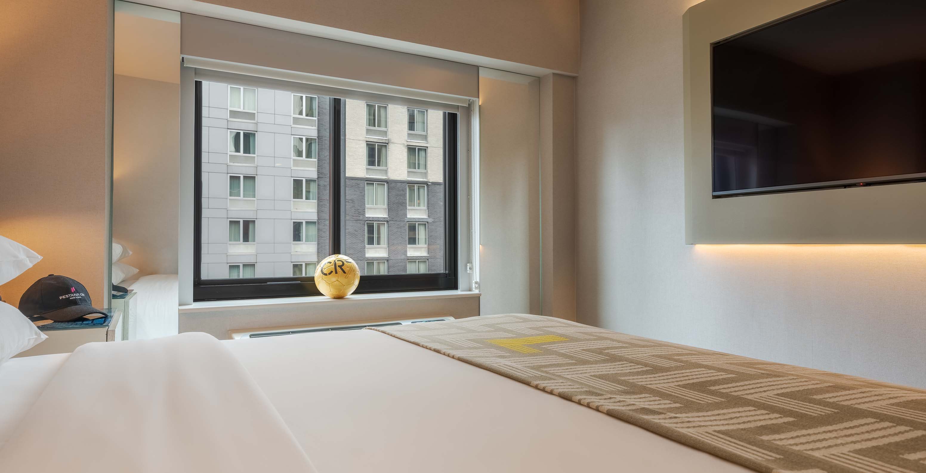 The Comfort Street View ADA at Pestana CR7 Times Square has a double bed with a bedspread with the number seven, and a window