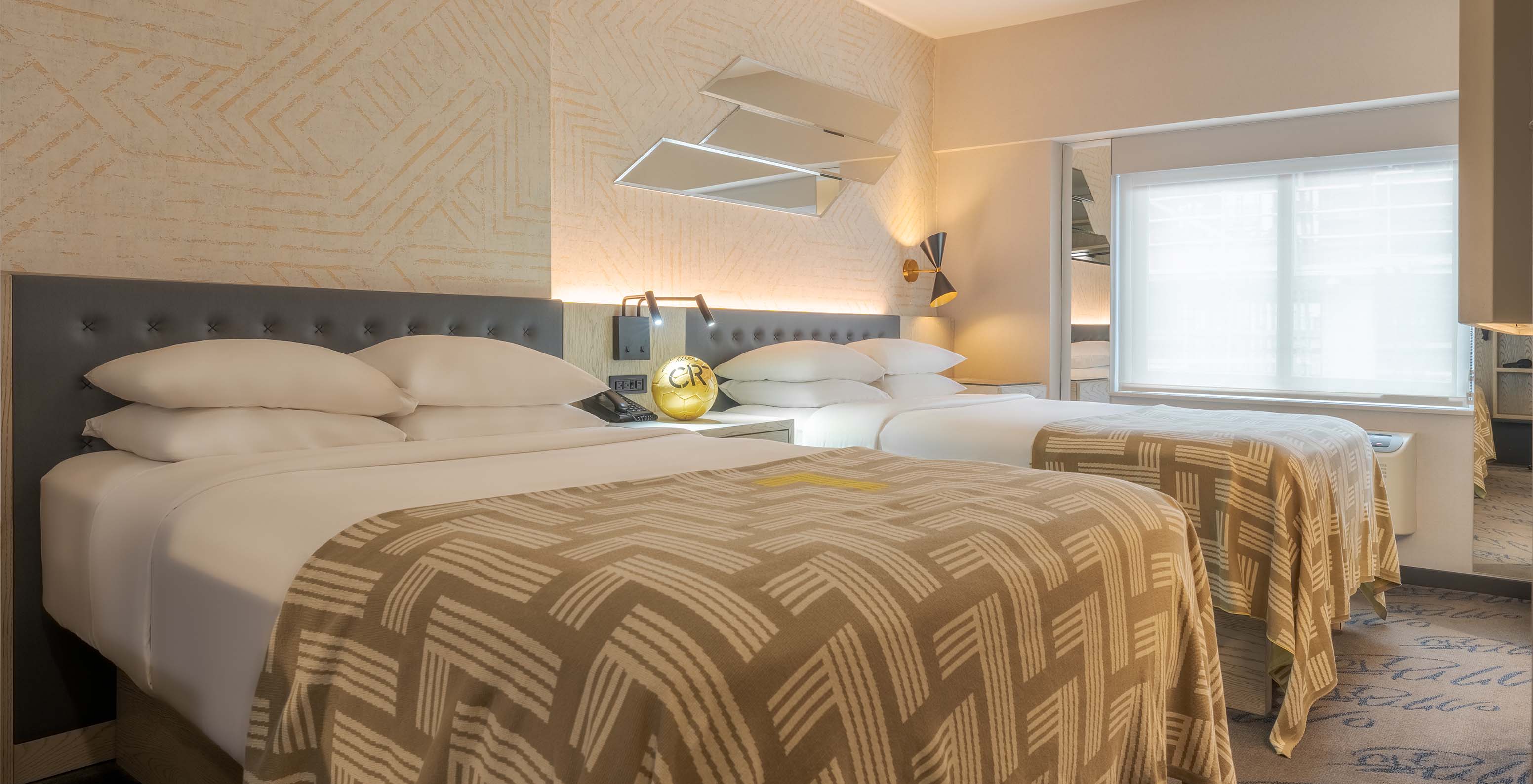 The Superior Double at Pestana CR7 Times Square has two beds with a bedspread with the number seven and a window