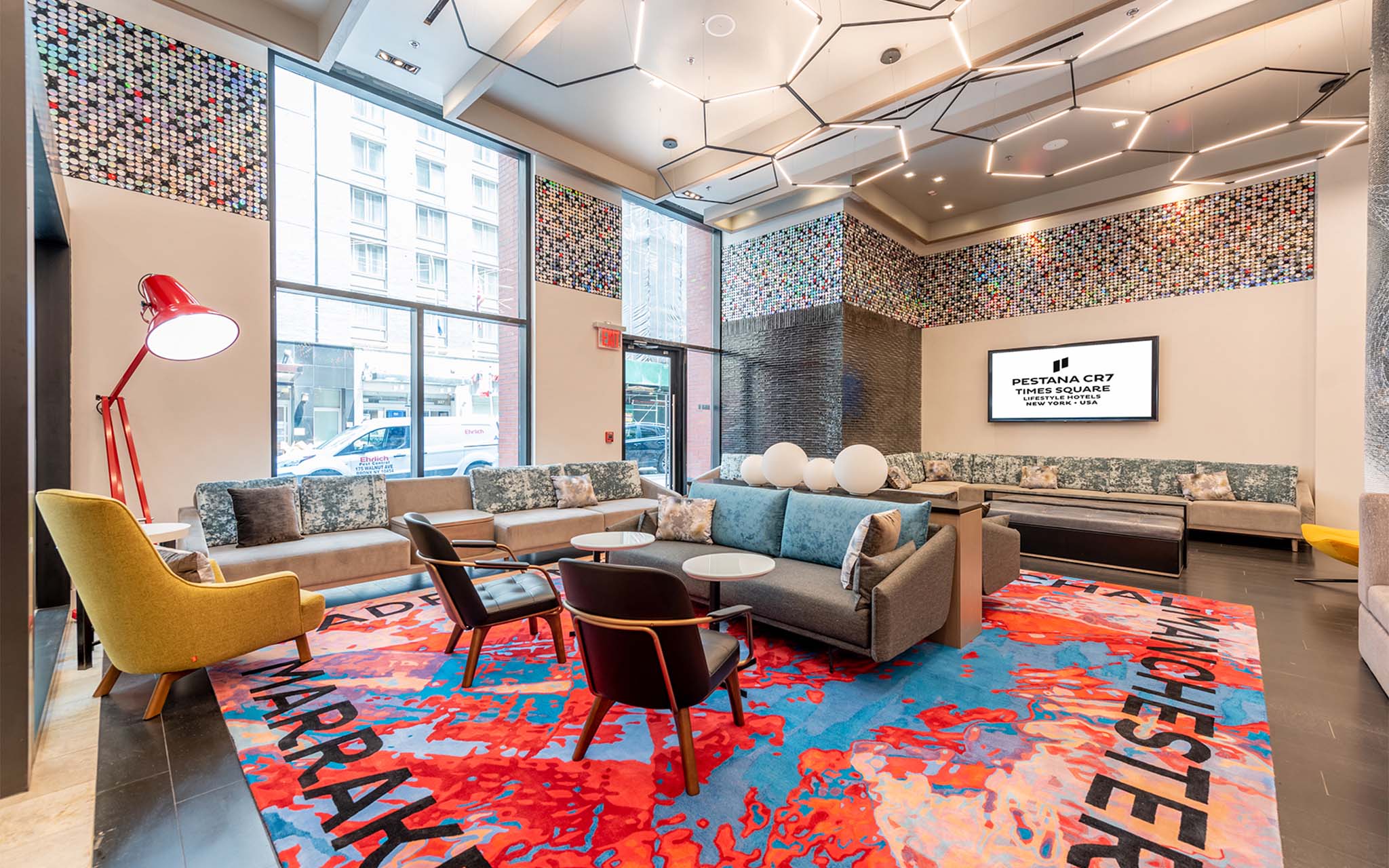 Entrance lobby of Pestana CR7 Times Square Interior view of the lobby of Pestana CR7 Times Square, with comfortable sofas, chairs, and a vibrant rug