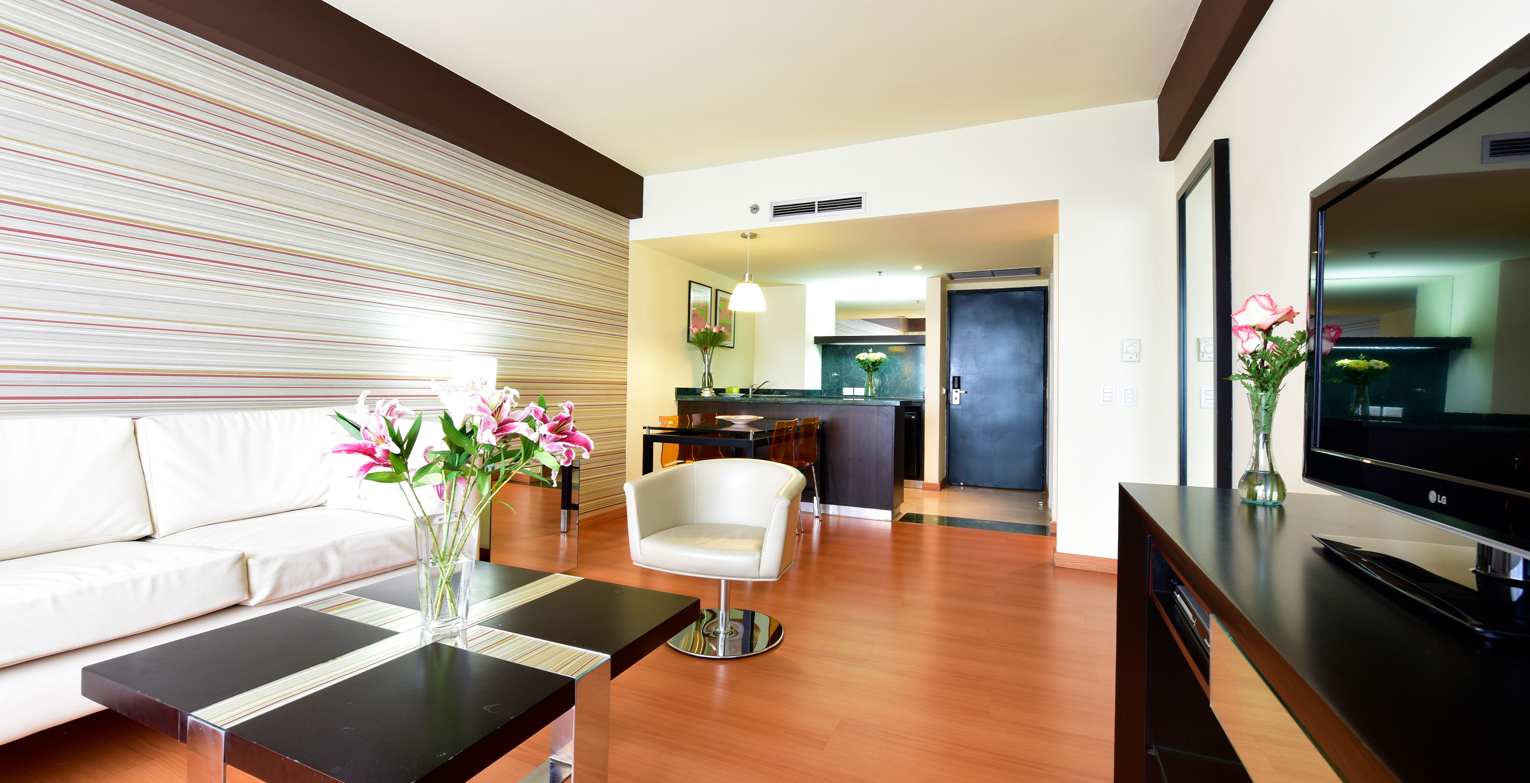 The King Junior Suite at Pestana Caracas has a living room with a comfortable white sofa, a side table, and a TV