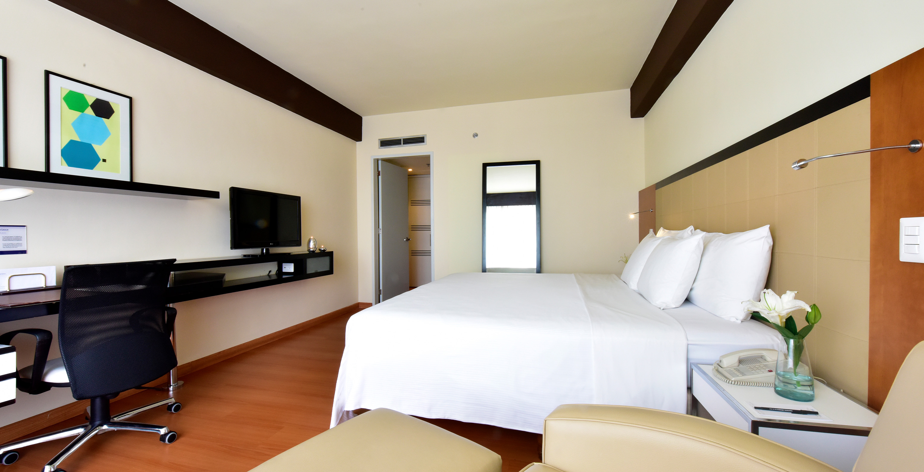 The Twin Superior Room at Pestana Caracas has a double bed, a mirror, a desk, and an armchair