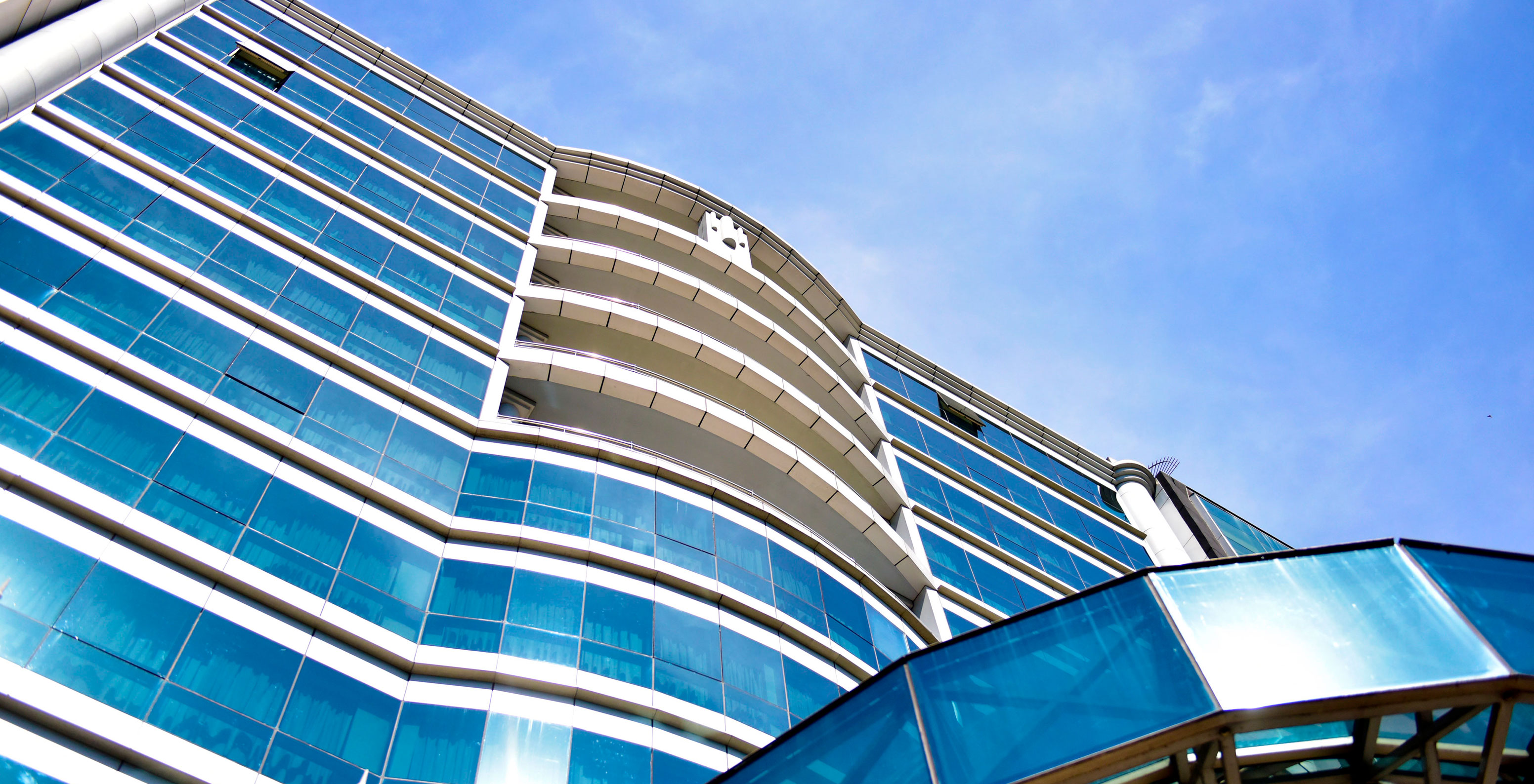 Fachada de vidrio azul del Pestana Buenos Aires y entrada moderna bajo un cielo claro