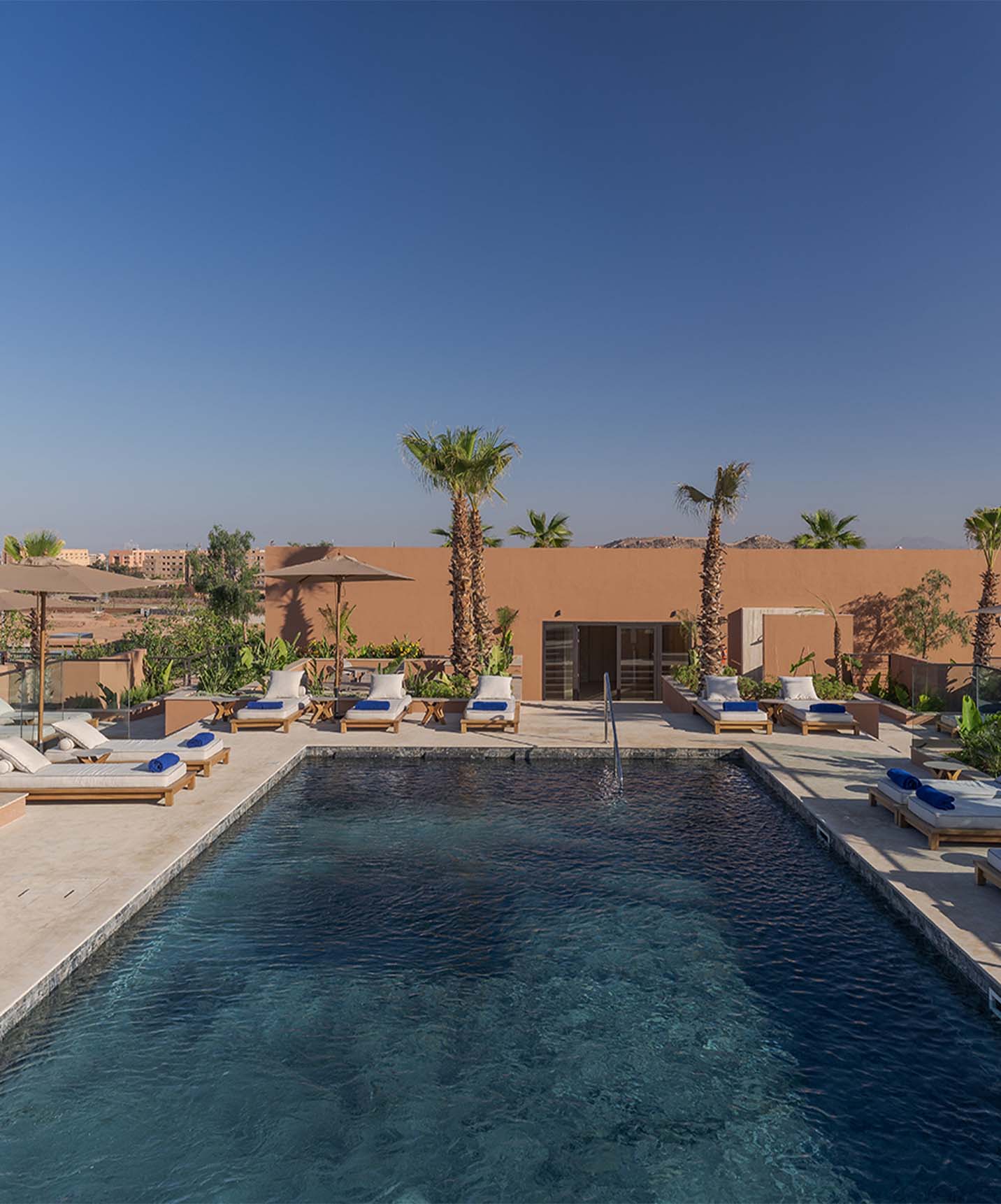 Piscina exterior en la azotea, con varias tumbonas con toallas y vista panorámica, del hotel lifestyle en Marruecos