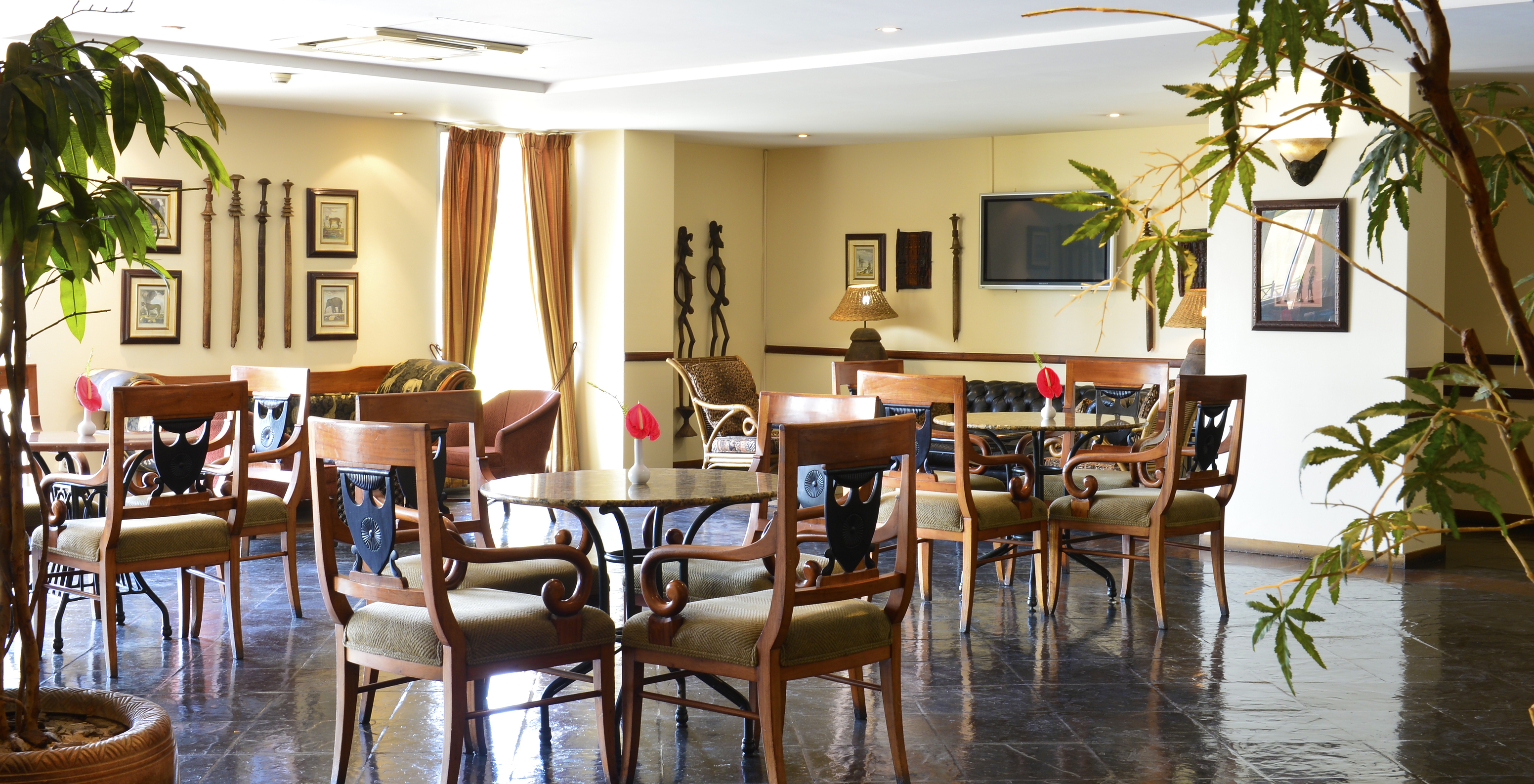 El restaurante Piazza del Campo, del Hotel 4 Estrellas en Maputo, tiene varias mesas redondas con una flor roja