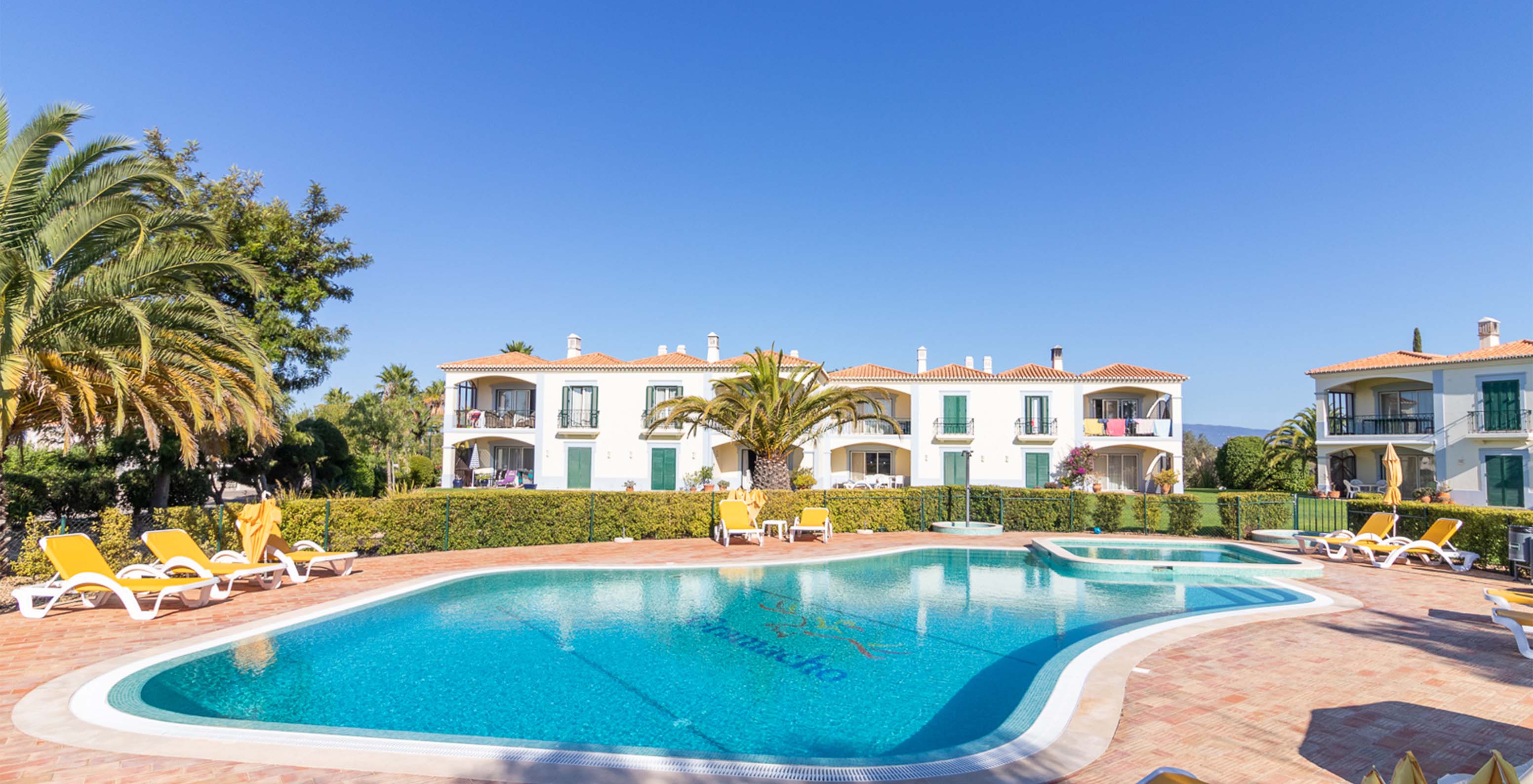 Piscina exterior común, con varias tumbonas amarillas del Pestana Carvoeiro, hotel en Carvoeiro cerca de campos de golf