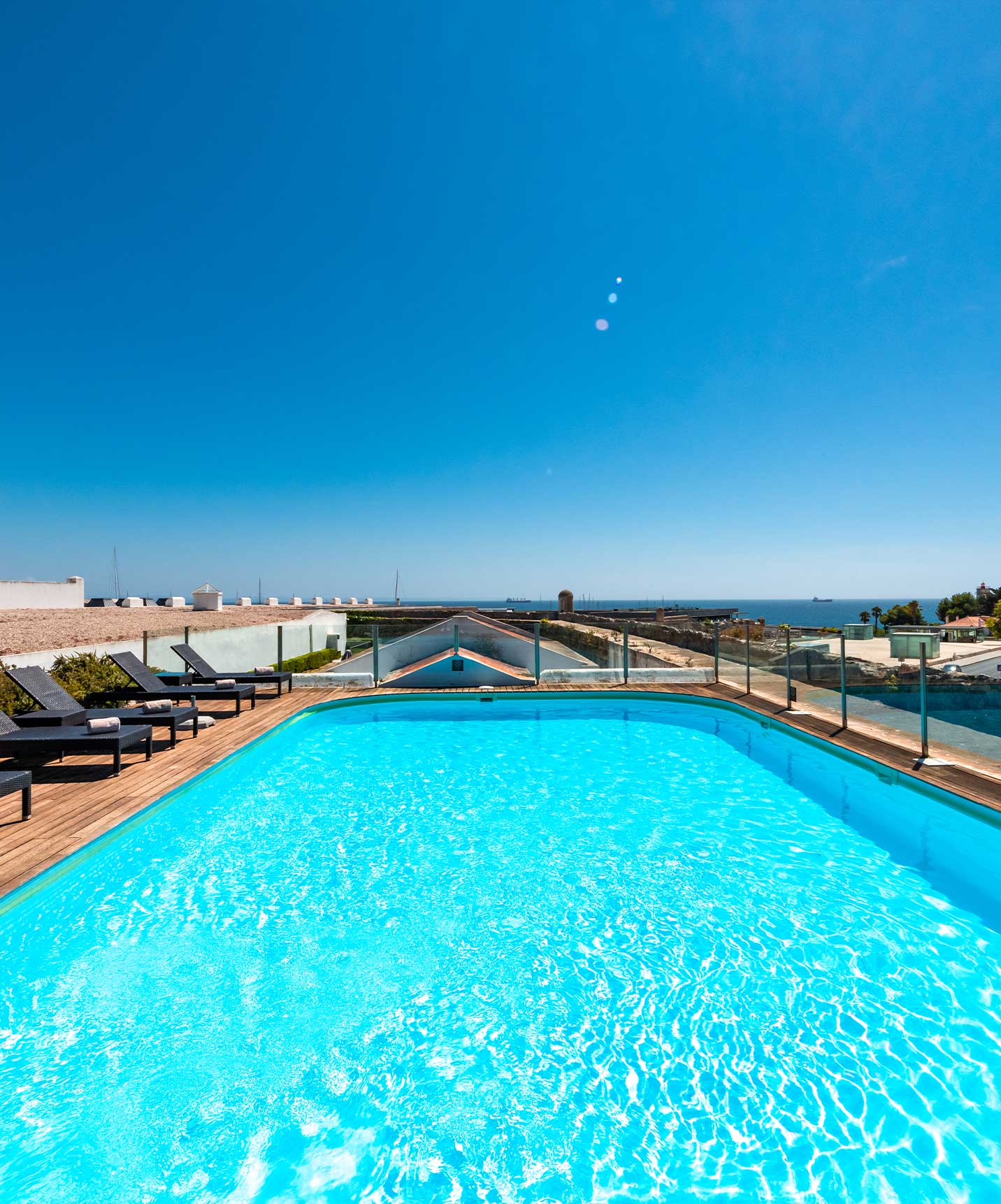 Piscina exterior con tumbonas en hotel de 5 estrellas en Cascais, con vista al mar