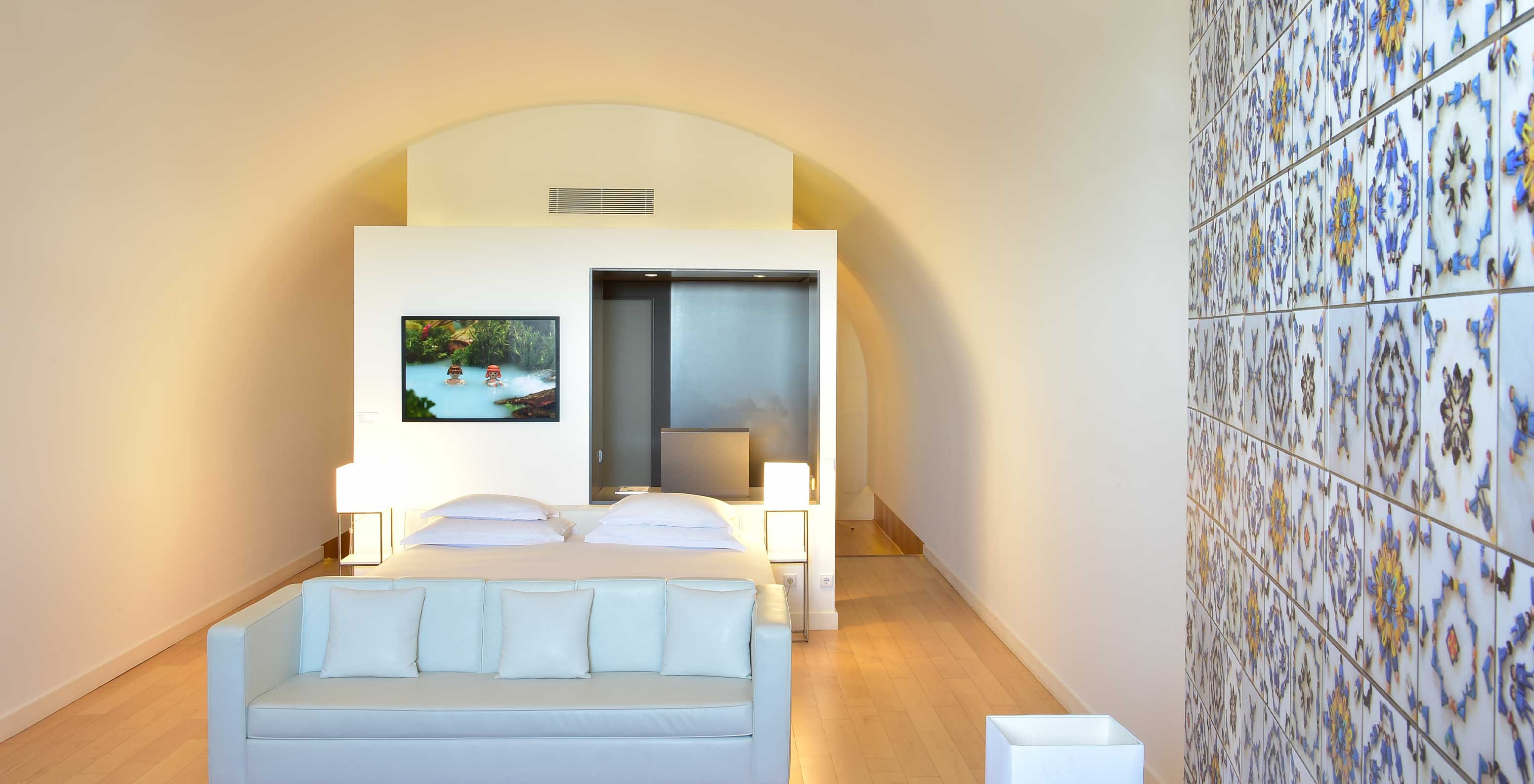 La Junior Suite Art District del Pestana Cidadela Cascais tiene una cama doble con sofá blanco y un cuadro en la pared