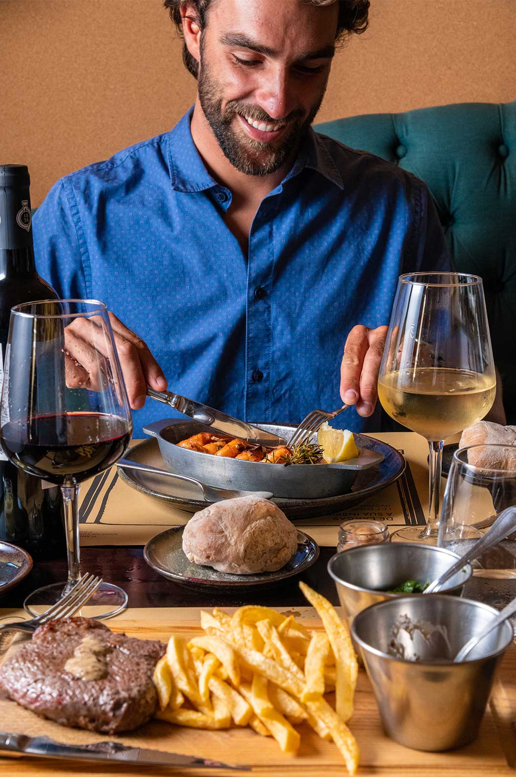 Pareja cenando en restaurante de hotel con spa y piscina, que sirve comidas como carne con papas fritas, camarones y vino