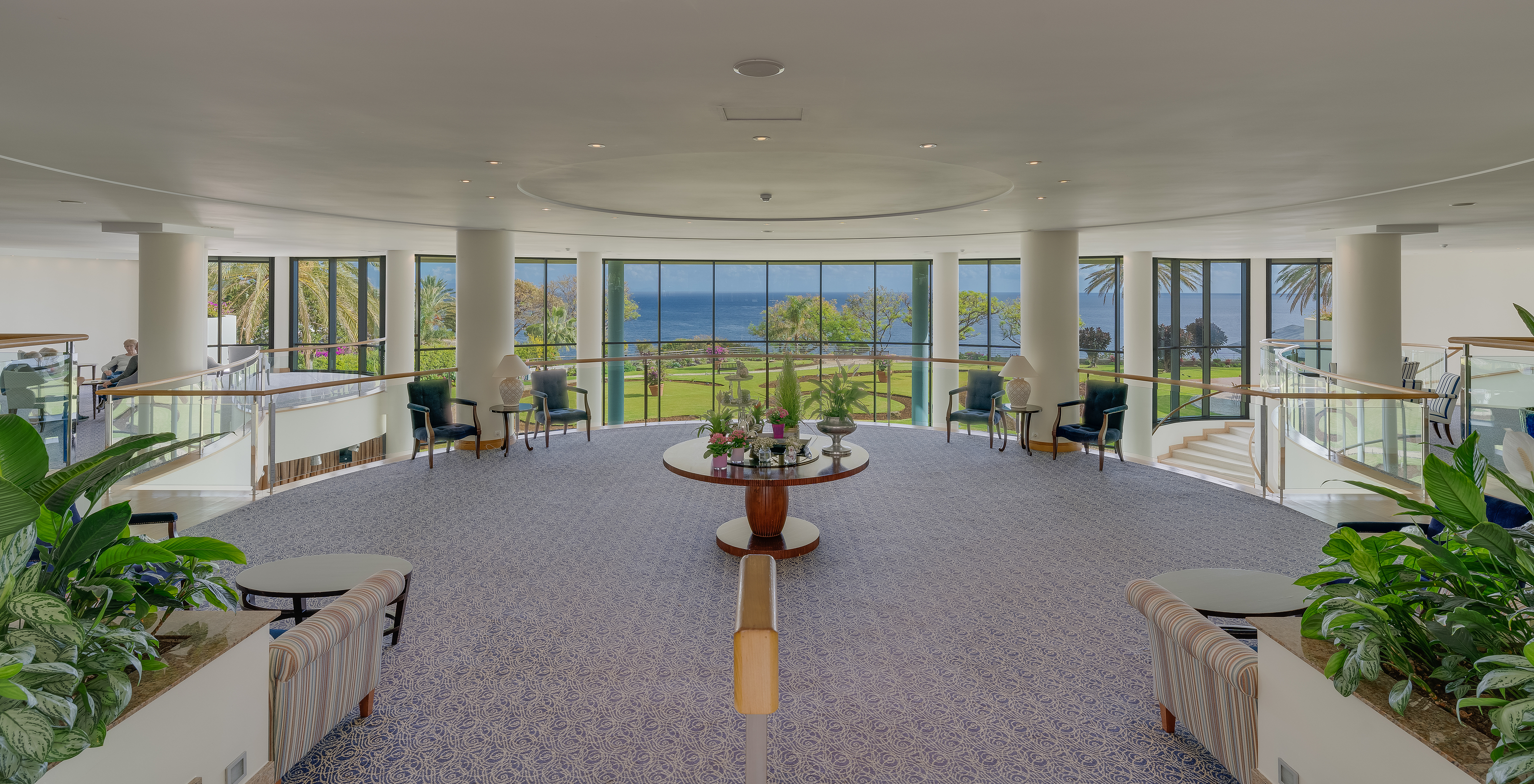 Pestana Grand, hotel con spa y piscina, frente al mar, tiene un lobby con vista al mar, con sillas y mesas