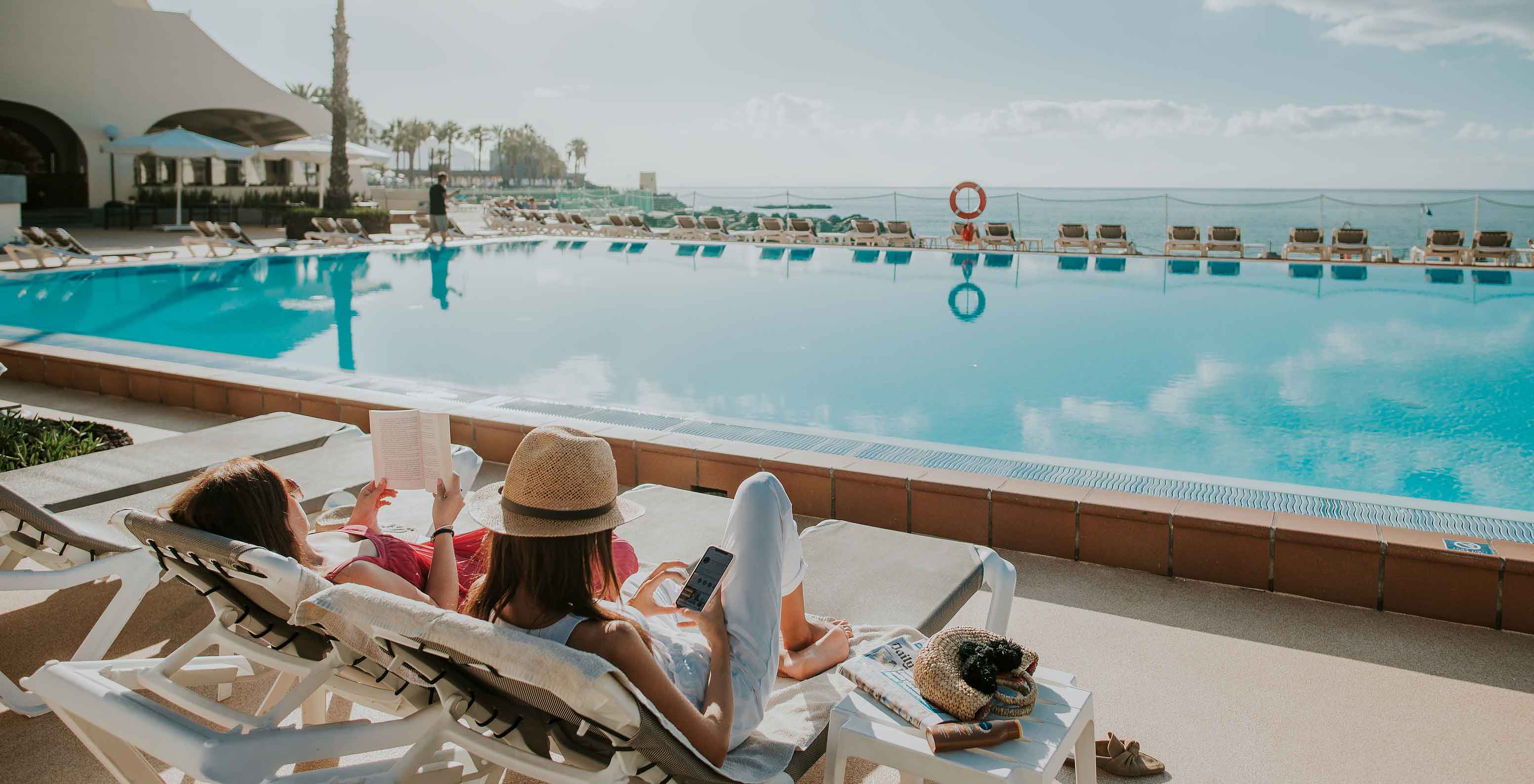 Dos señoras en tumbonas junto a la piscina del Pestana Madeira Beach Club, un resort premium