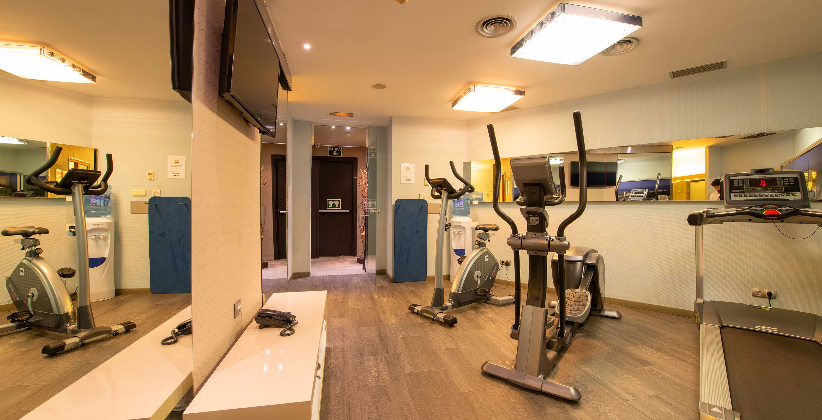 El hotel en Barcelona tiene un gimnasio para sus clientes con algunas máquinas, un espejo y una televisión