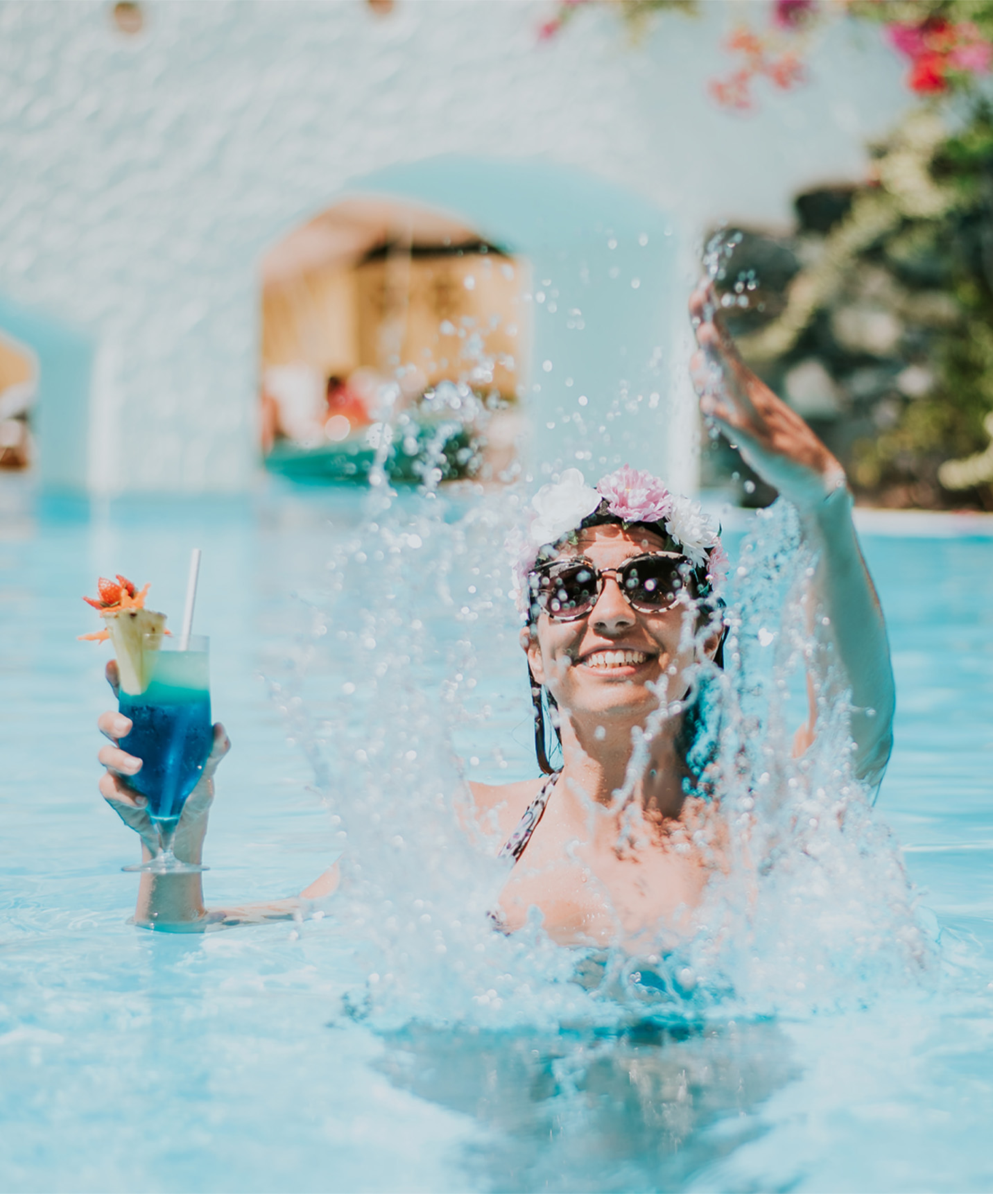 Mujer feliz jugando con el agua, con un cóctel en la mano, disfrutando del paquete todo incluido sin preocupaciones