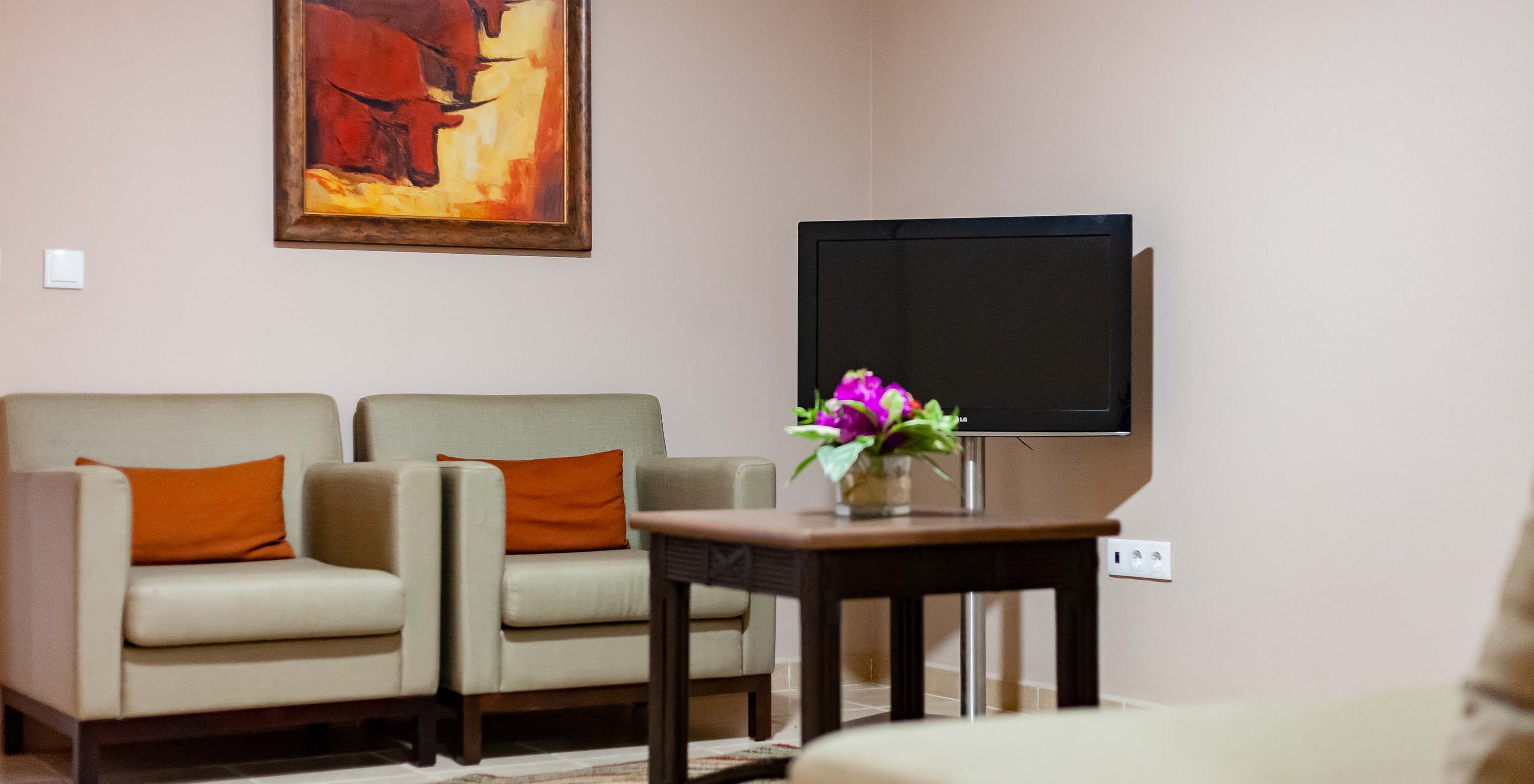 The Junior Suite at Pestana Tropico features two armchairs, a coffee table, and a television