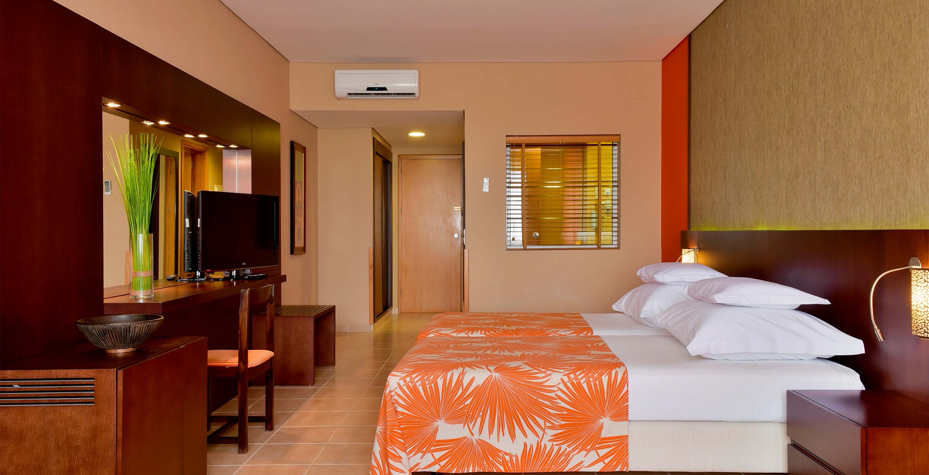 The Standard room at Pestana Tropico features two single beds, television, bedside table, mirror, and a chair