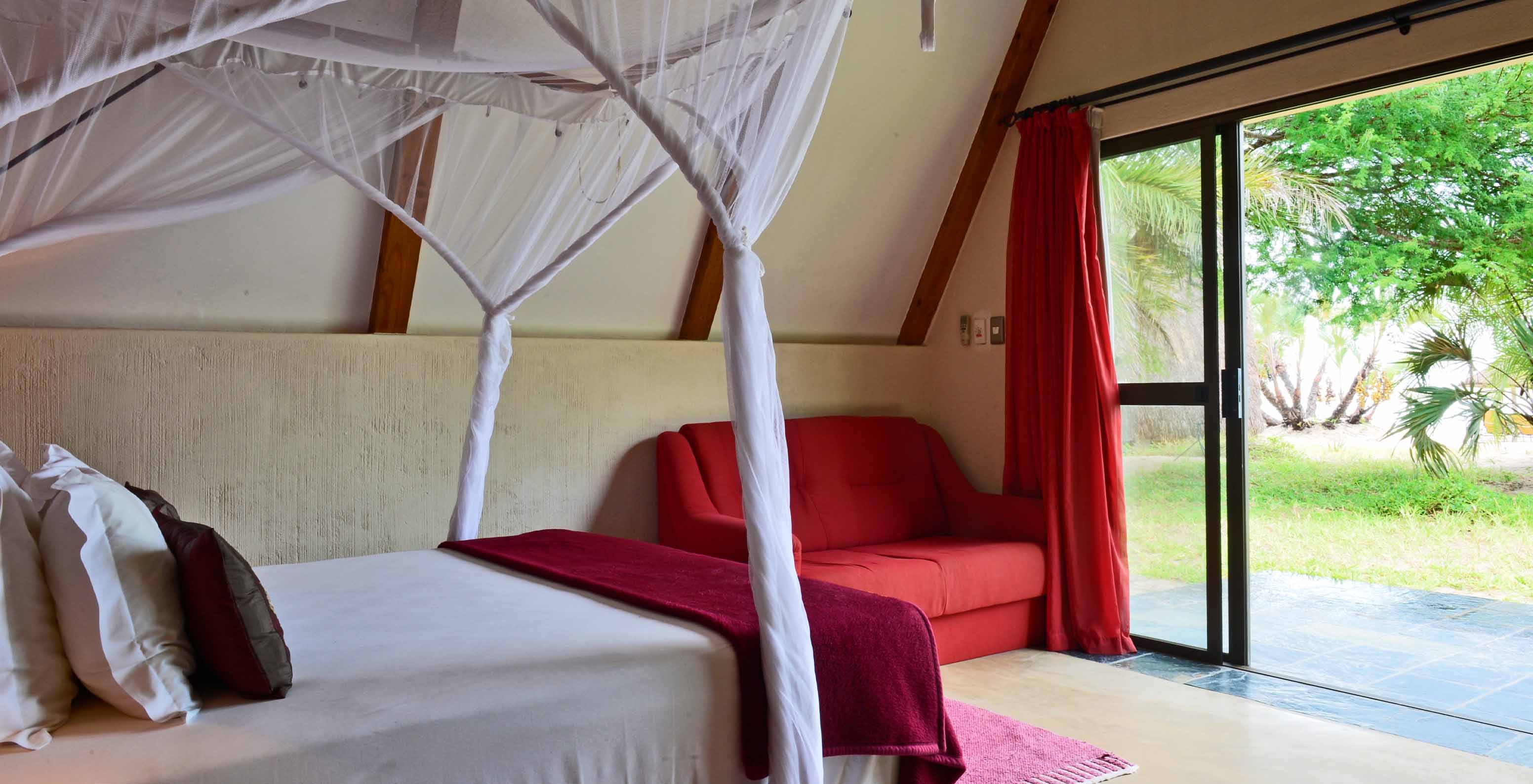 El Bungalow Suite T2 del Pestana Bazaruto Lodge tiene cama con dosel y vista al jardín, y un sofá doble al costado