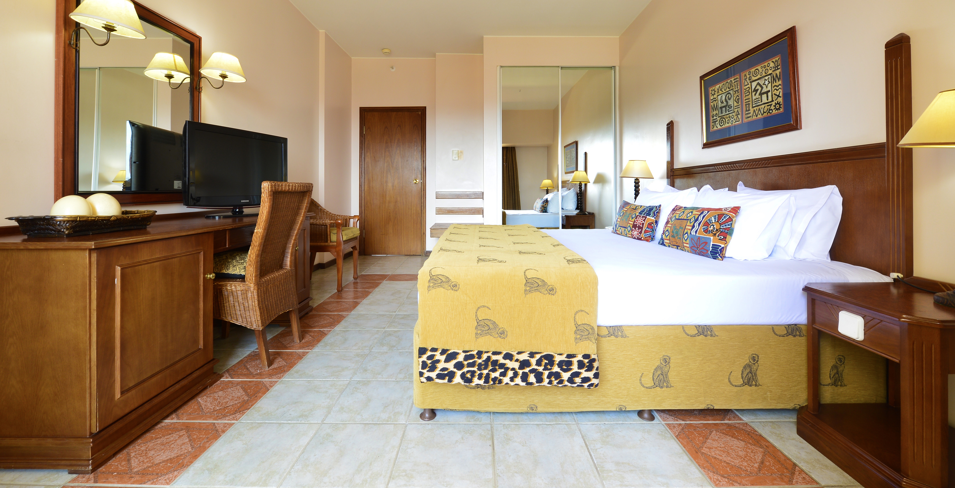 La Suite Luxo del Pestana Rovuma tiene una cama y un cuadro con decoración típica africana, un escritorio y televisión