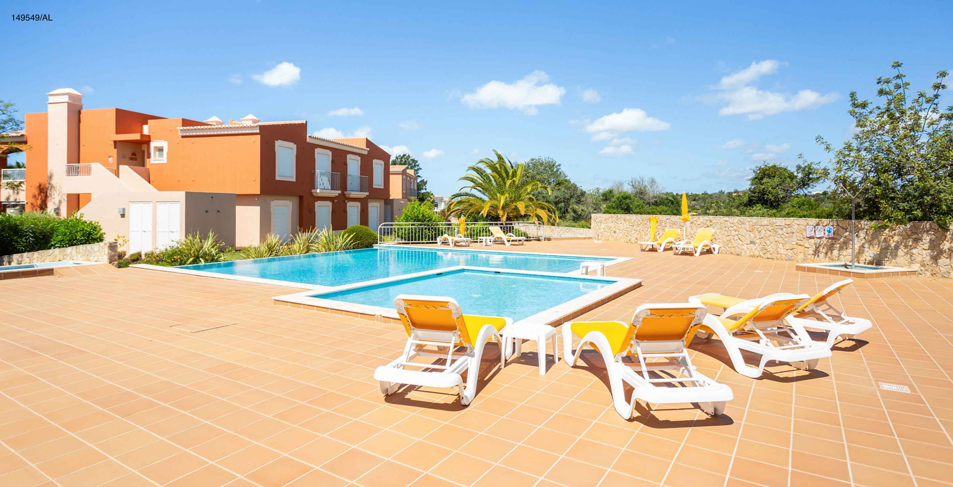 El apartamento Pestana Carvoeiro Golf T2 Superior tiene un patio exterior con piscina y tumbonas amarillas