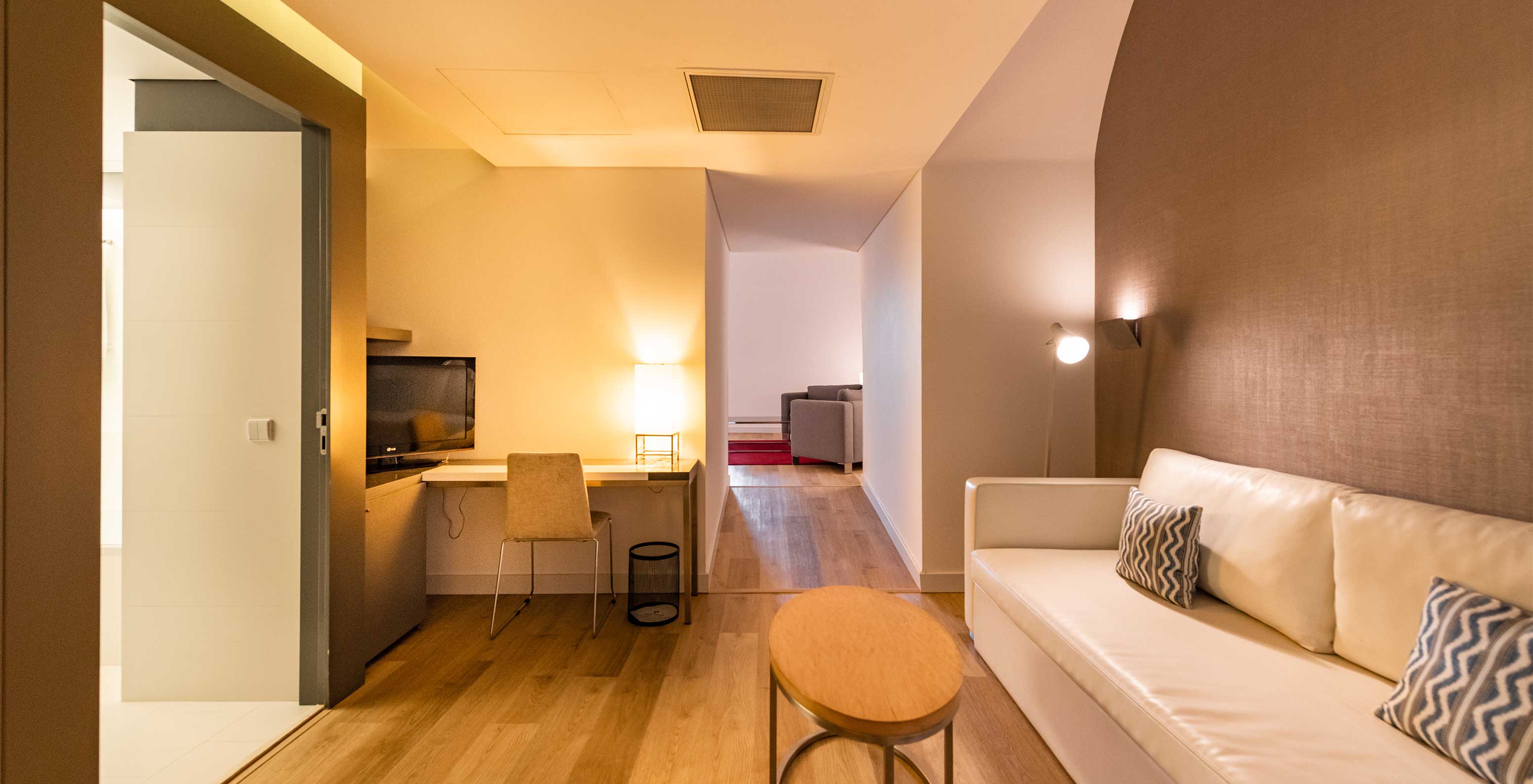 La Junior Suite Familiar del Pestana Cidadela Cascais tiene una sala con un sofá, una mesa auxiliar y un escritorio