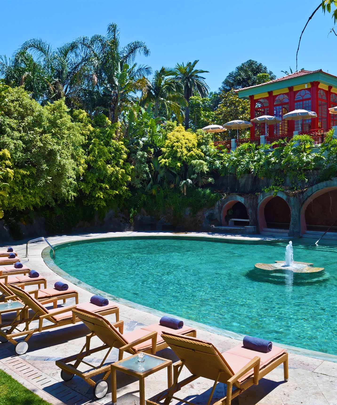 Piscina exterior con una fuente central y tumbonas en el Palace Lisboa, hotel en un palacio en Lisboa, con piscinas y spa