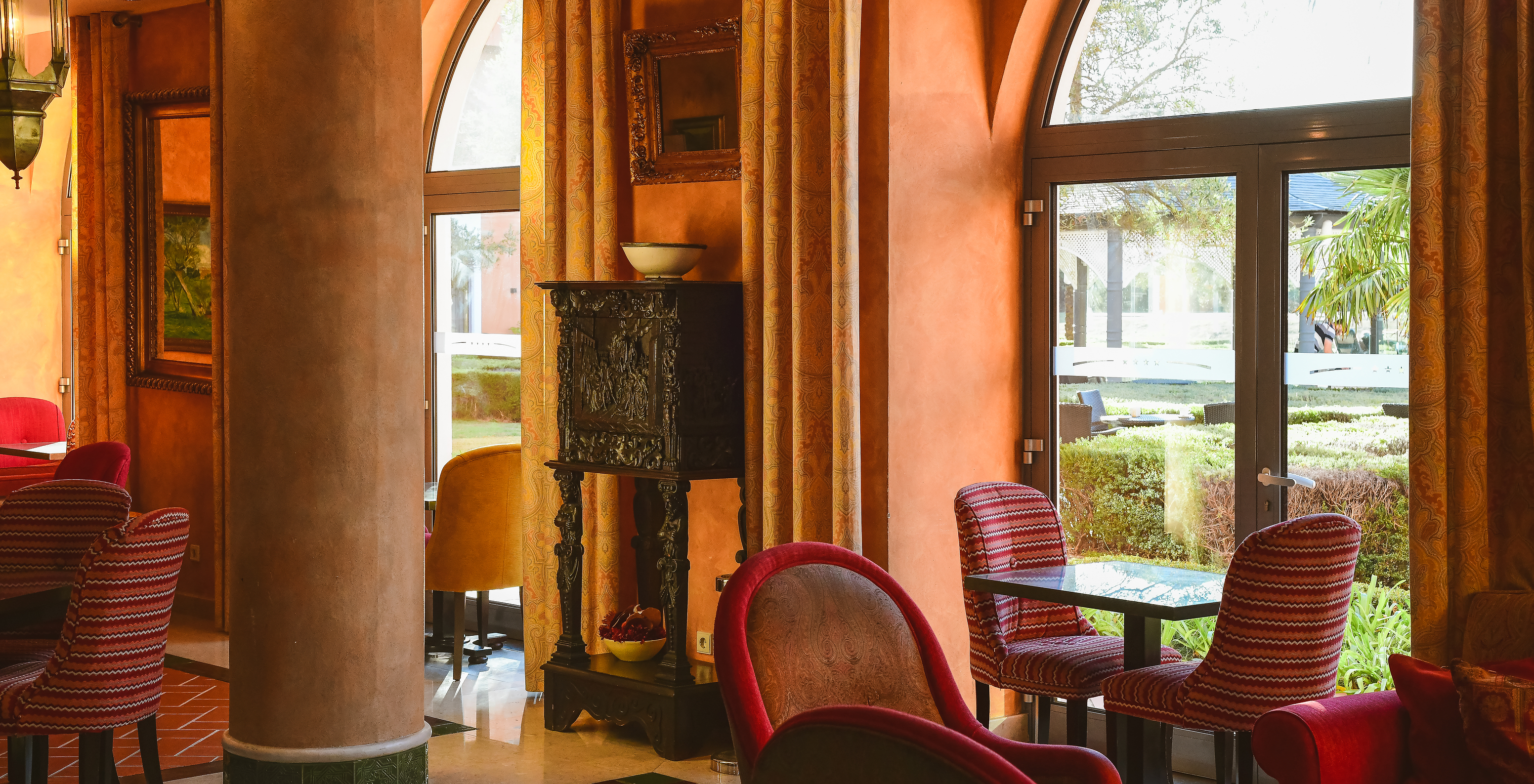 El restaurante Mourisco, del Hotel 4 Estrellas en Sintra, tiene mesas, una columna y ventana con vista a la piscina exterior