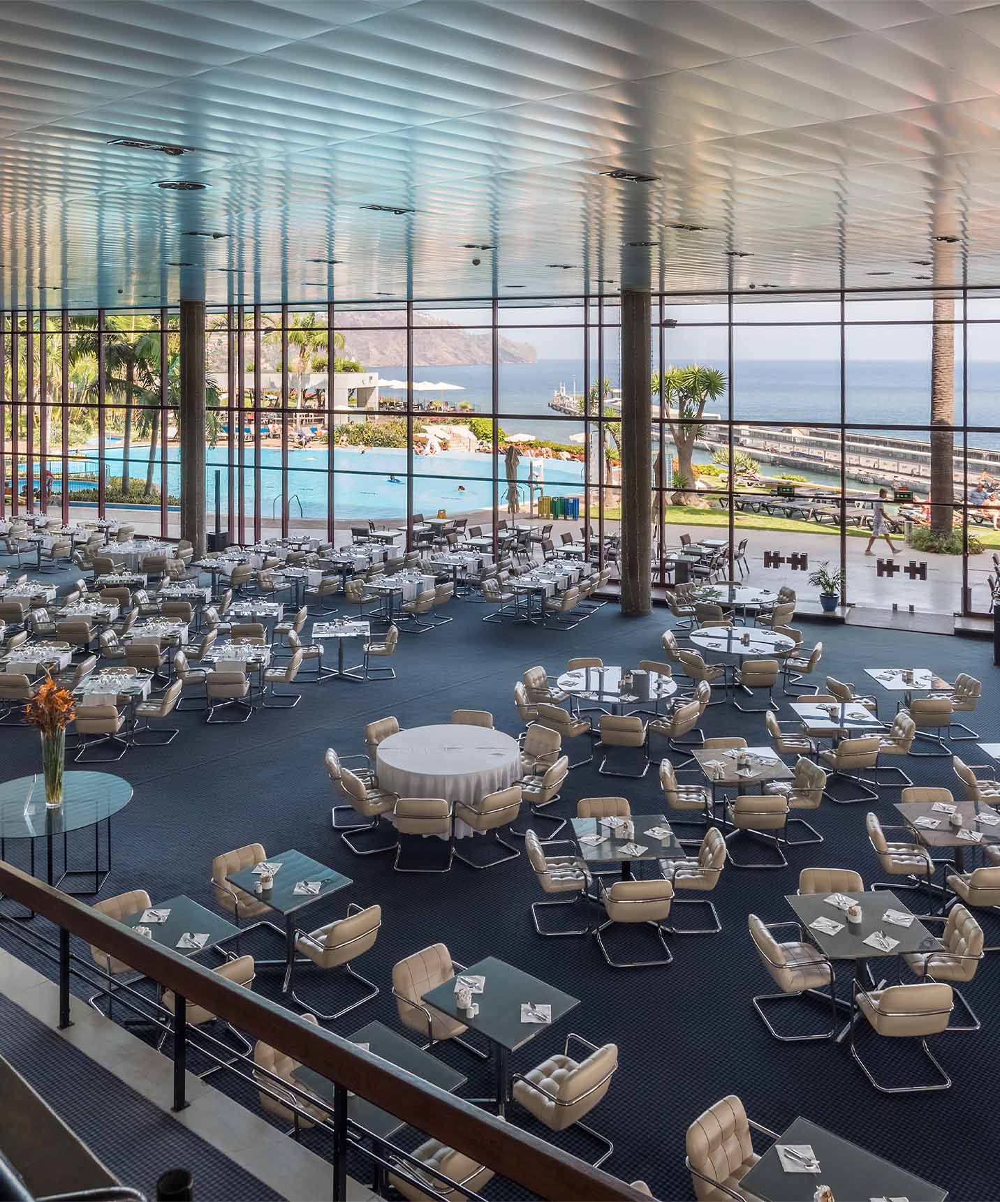 Vista de arriba de un restaurante del Pestana Casino Park, con varias mesas, y vista a la piscina y al mar