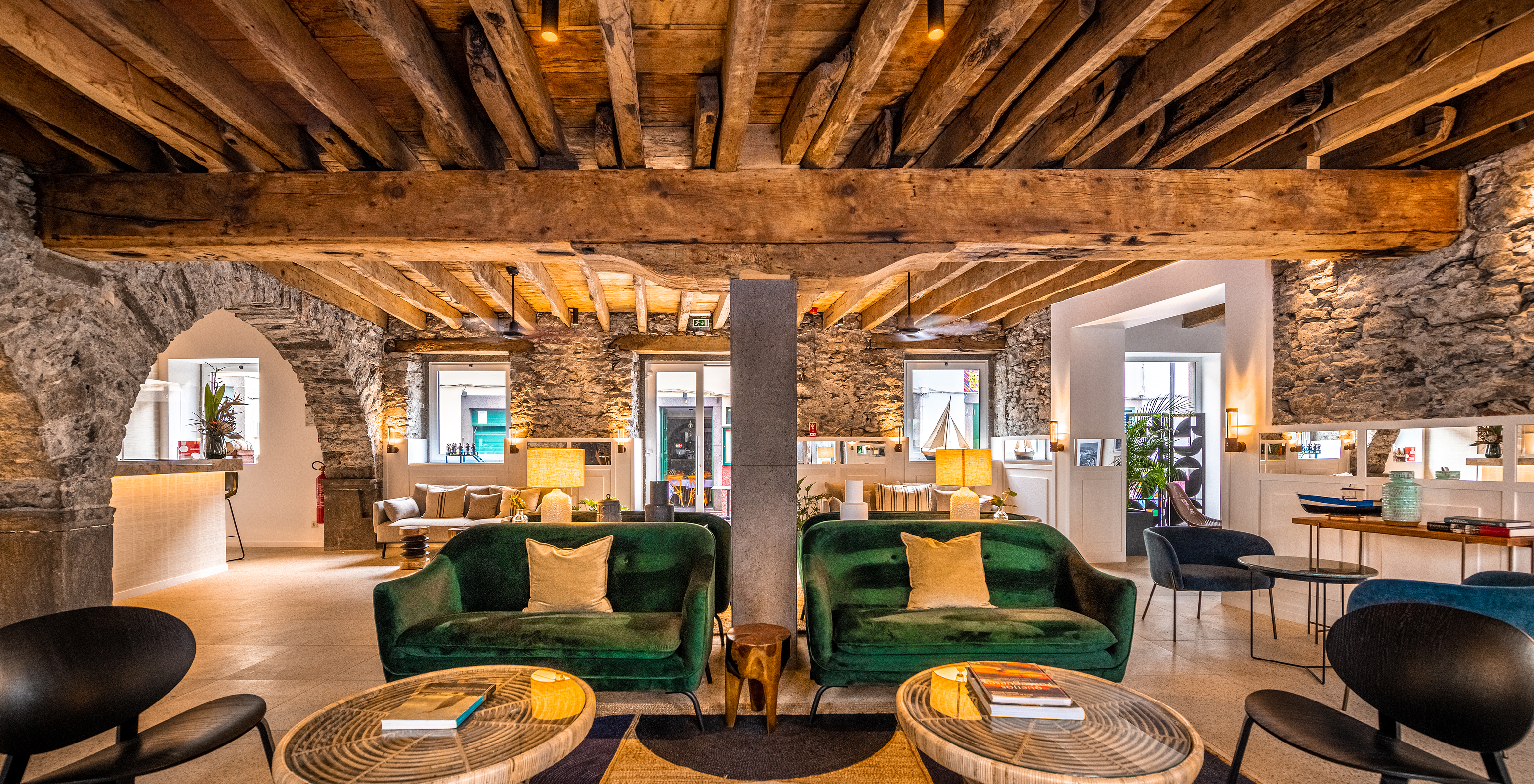 Recepción del Hotel Boutique en el Centro Histórico de Câmara de Lobos, con sofás, paredes de piedra y techo de madera