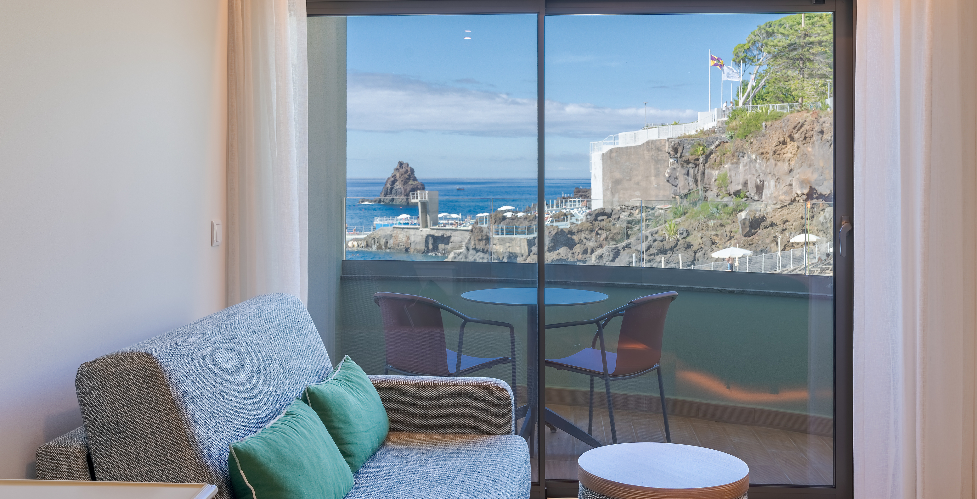 El Clásico Vista Mar Lateral del Pestana Vila Lido Madeira tiene un sofá al lado del balcón con vista lateral al mar