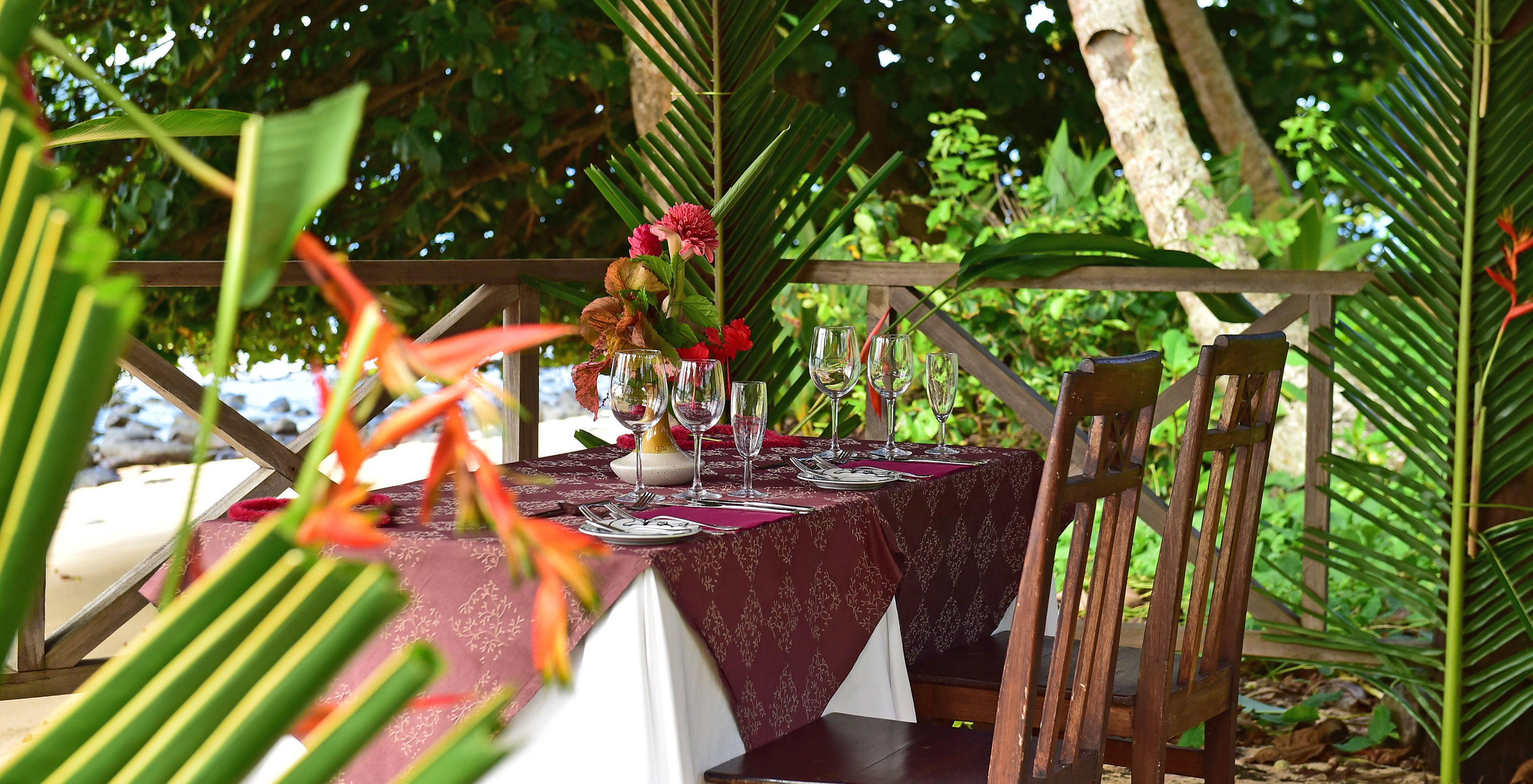 Restaurante del hotel para vacaciones con piscina y spa frente a la playa rodeado de flores y vegetación verde