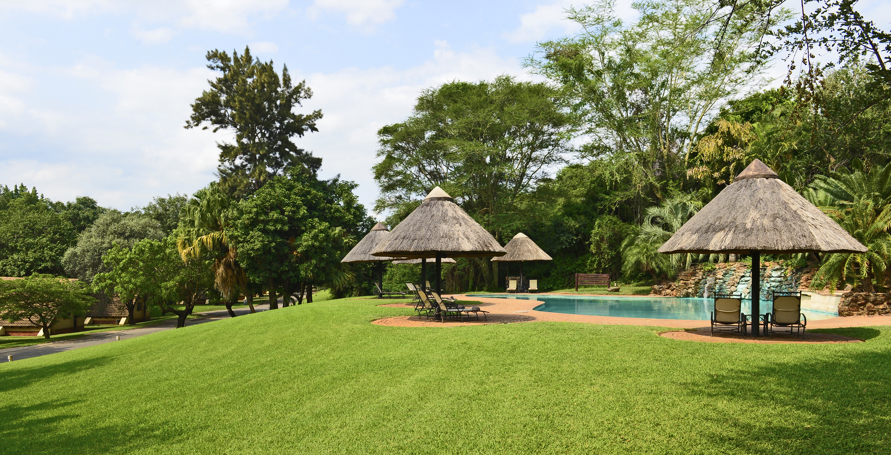 Piscina exterior con tumbonas en los jardines del Pestana Kruger Lodge, hotel de 4 estrellas en el Parque Kruger