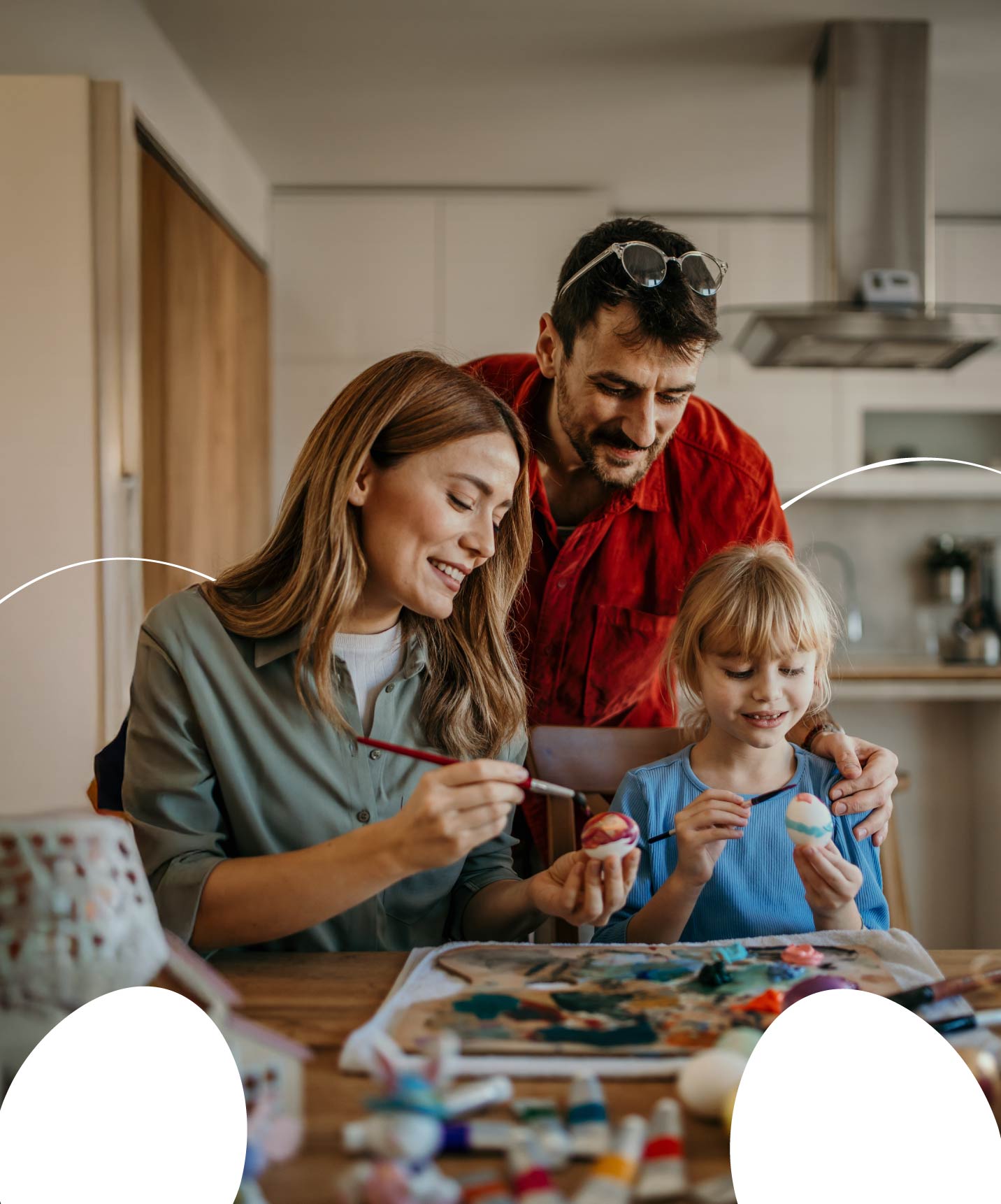 Padre, madre e hija reunidos pintando huevos de Pascua. Pase la Pascua en familia con Pestana Residences.