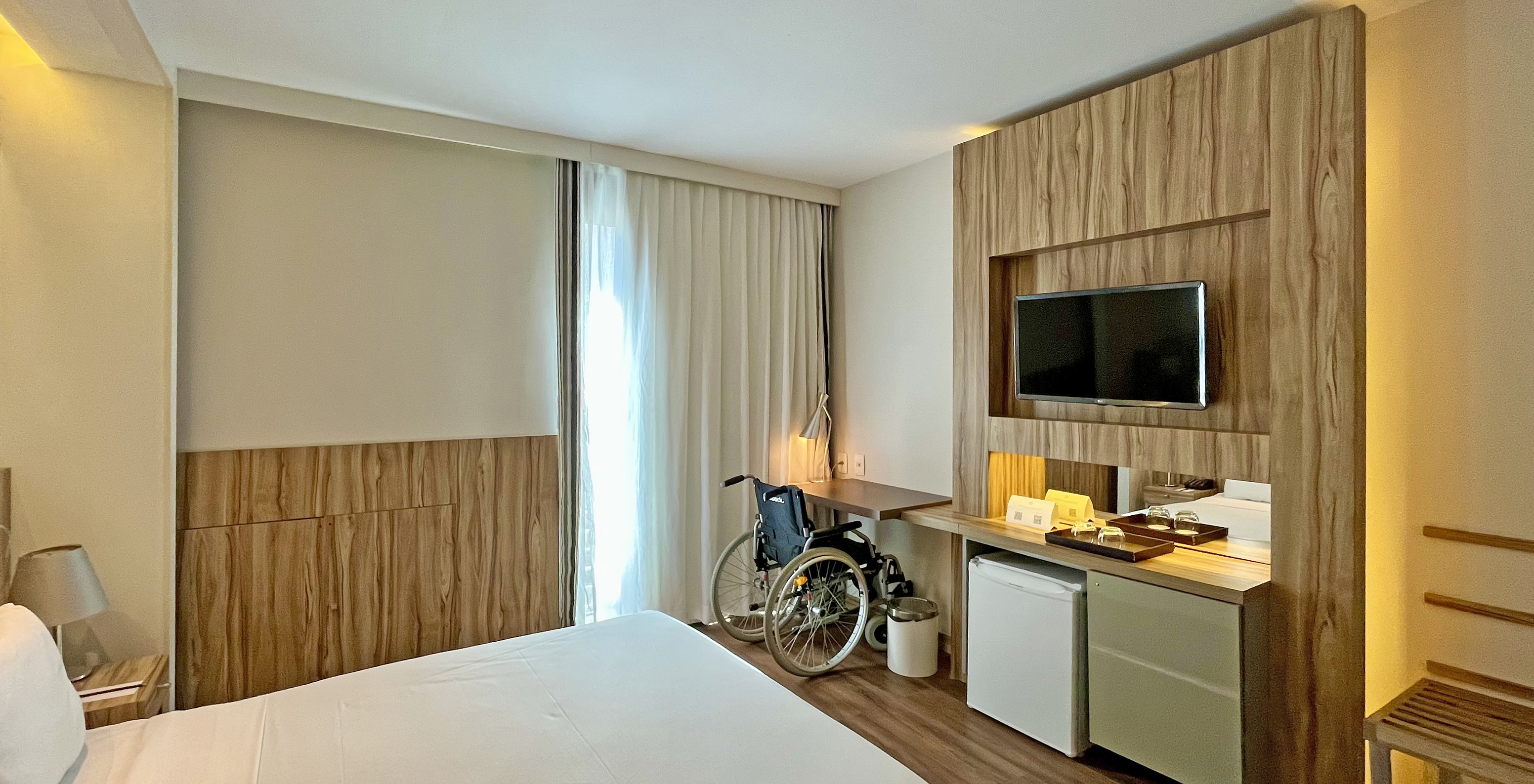 Le Chambre Adaptée du Pestana Rio Atlântica a un lit double et un bureau avec une chaise roulante