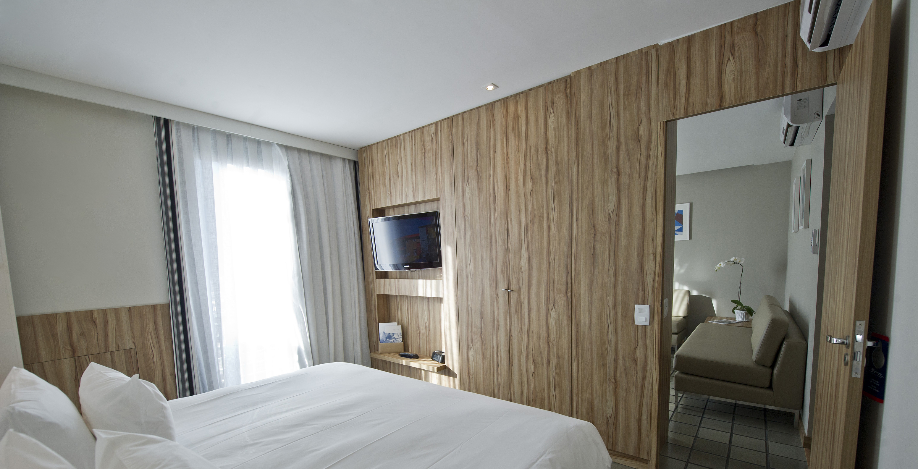 La Suite du Pestana Rio Atlântica a une chambre avec lit double et télévision, et un salon avec canapés et climatisation