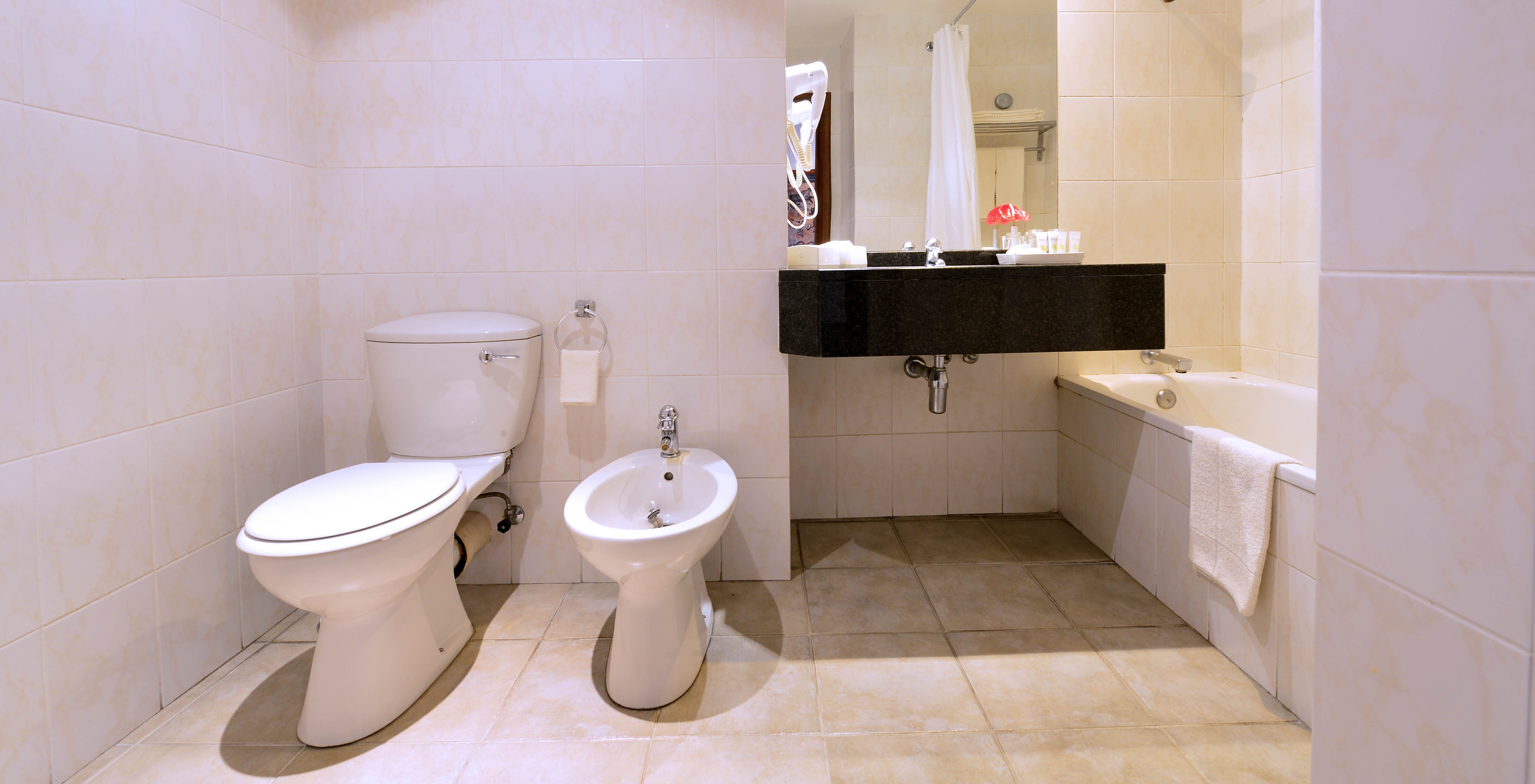 La Suite Luxe du Pestana Rovuma a une salle de bain avec toilettes, bidet, lavabo avec miroir et baignoire avec douche