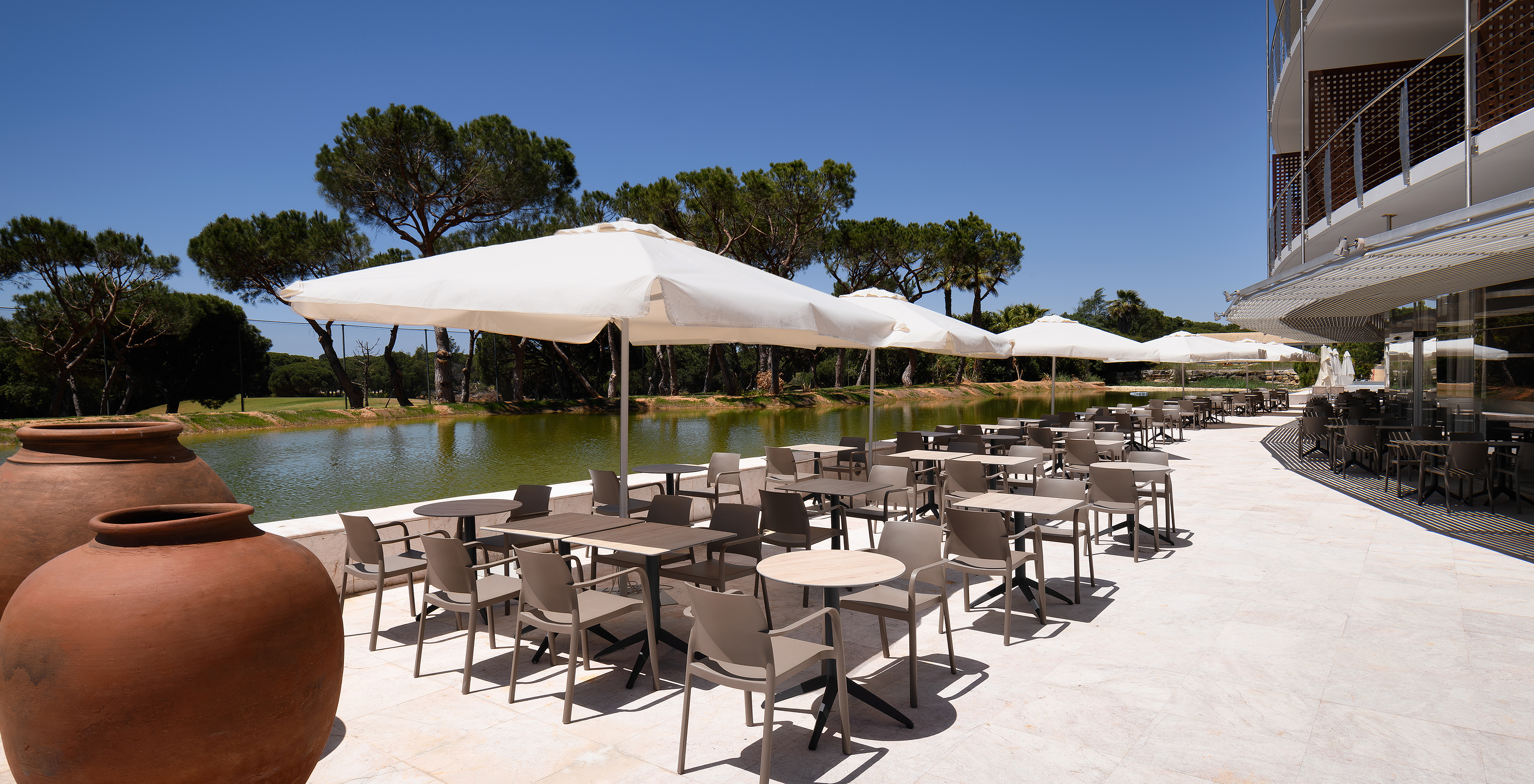 Terrasse avec tables, parasols et vue sur un lac au Pestana Vila Sol - Vilamoura, hôtel avec golf et spa en Algarve