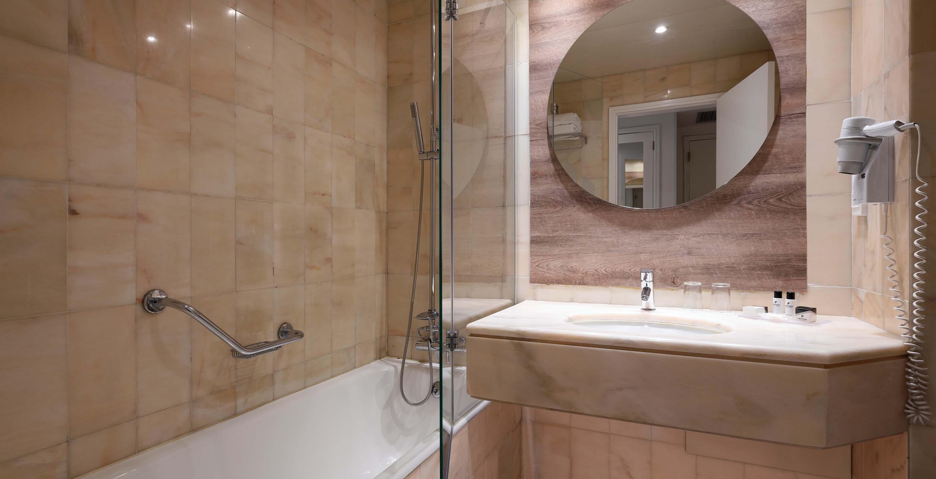 La chambre Deluxe Supérieure Vue Mer du Pestana Cascais a une salle de bains avec miroir, lavabo et baignoire avec douche