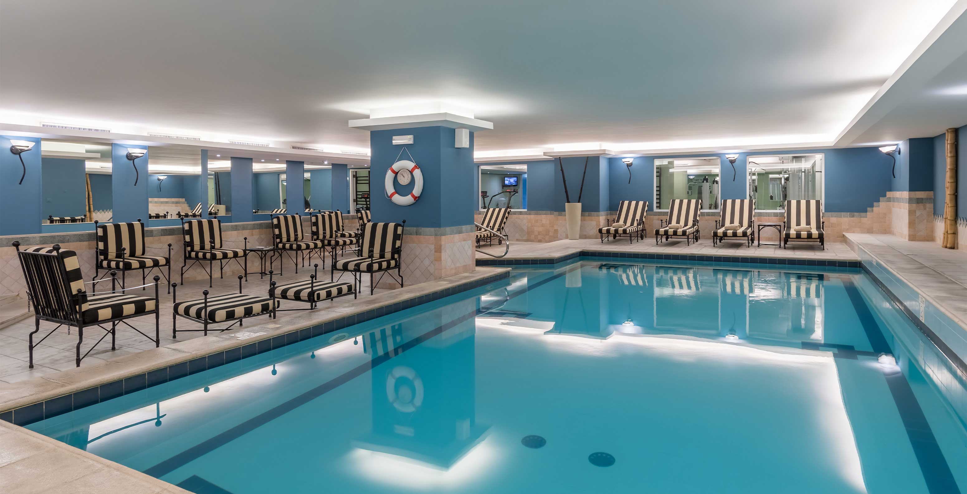 Le Pestana Carlton Madeira, un hôtel au centre de Funchal face à la mer, a une piscine intérieure avec des chaises rayées