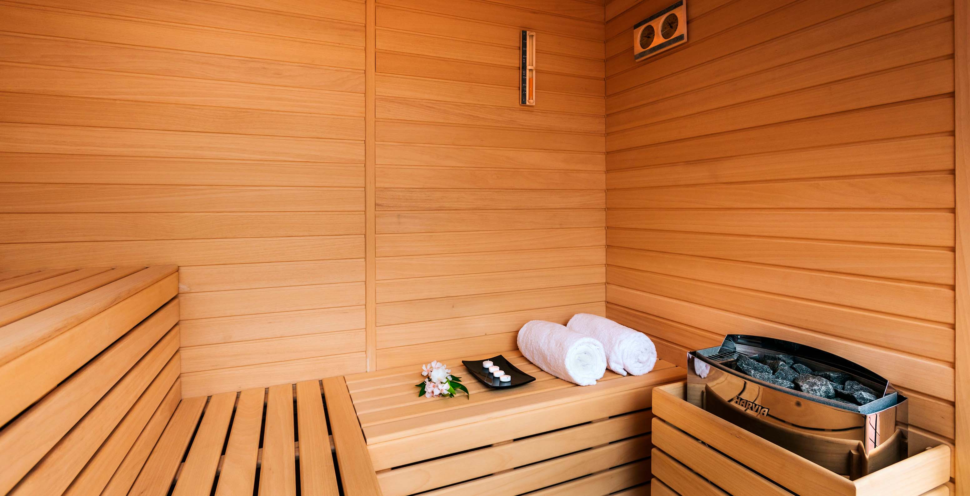 Zone de sauna en bois, avec deux serviettes et bancs où l'on peut se reposer et profiter du soin