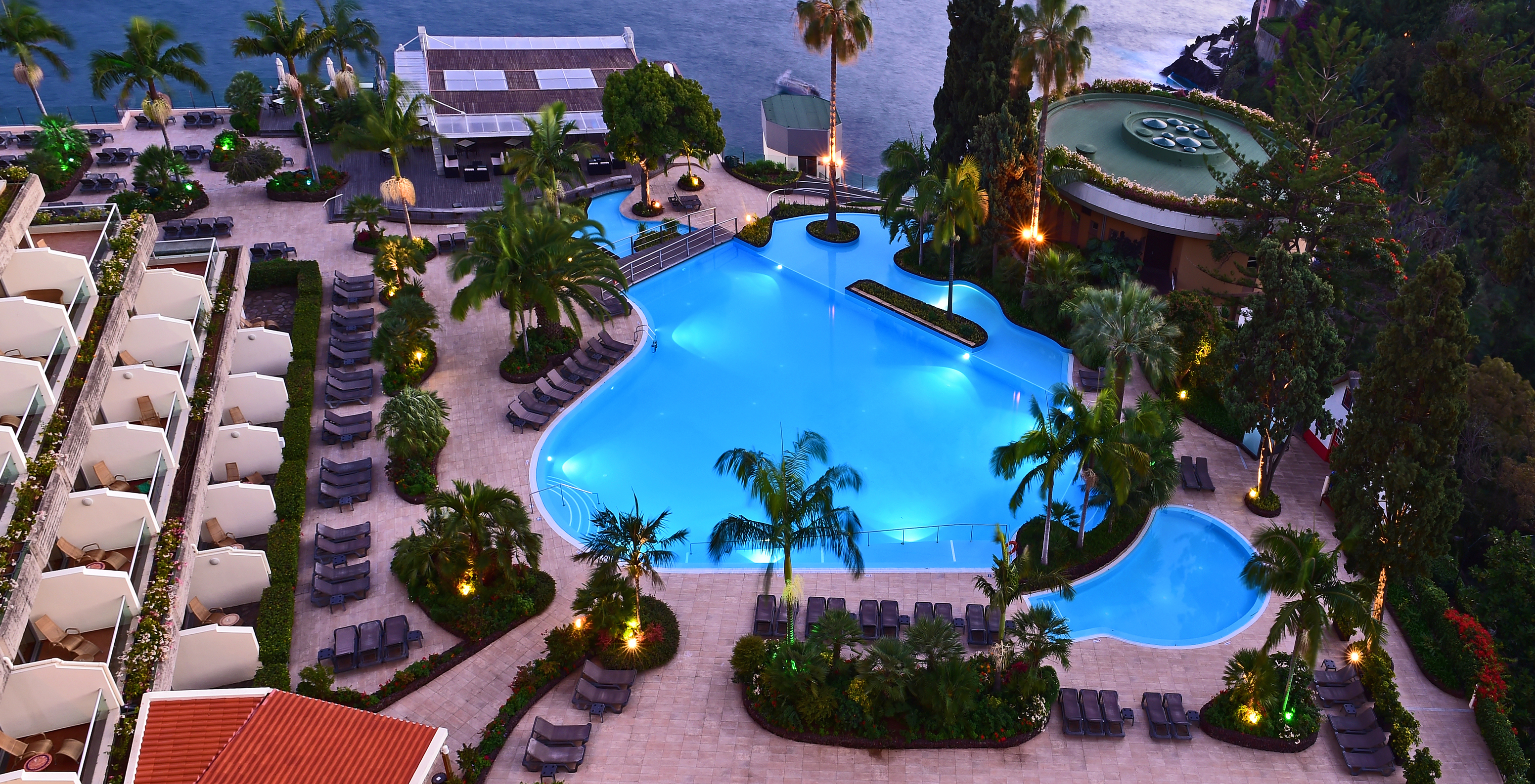 Vue aérienne de la piscine du Pestana Madeira Beach Club et des chaises longues face à l'océan Atlantique