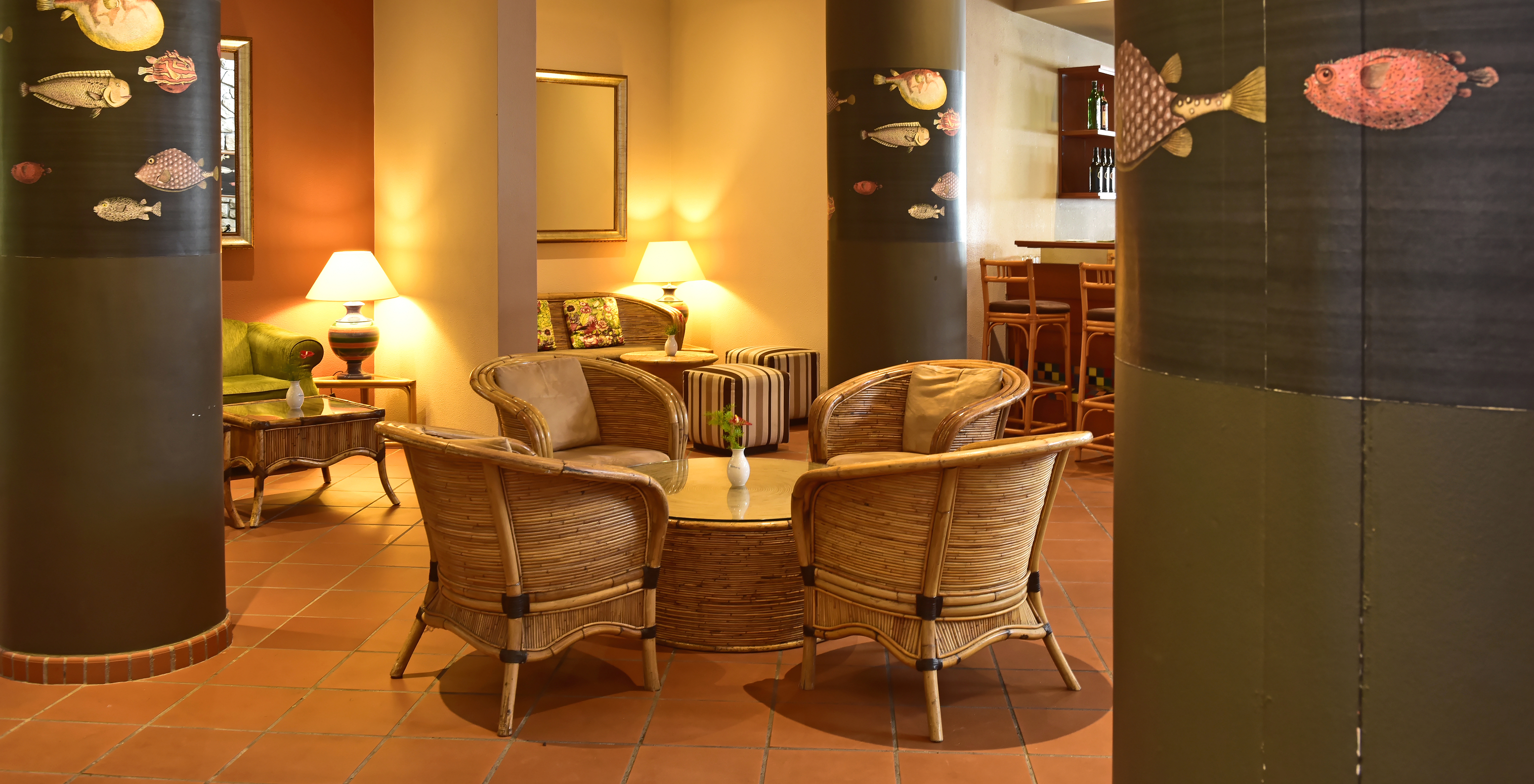 Le bar Arlequim, à l'Hôtel à Madère, a une table et des chaises en bambou et des colonnes avec des portraits de poissons