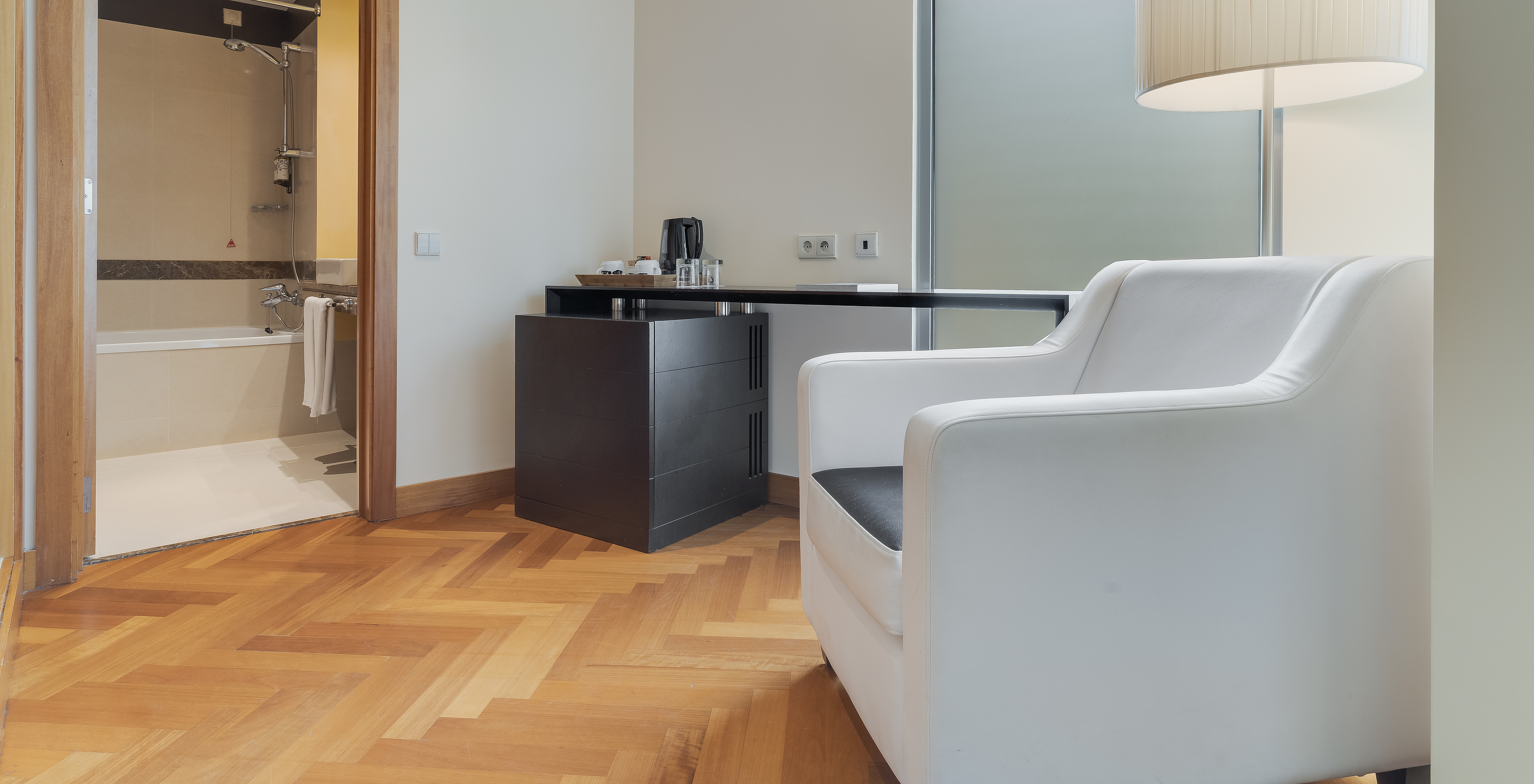 Le Twin Classique du Pestana Promenade a une salle de bain avec baignoire et a un fauteuil et une table à l'entrée